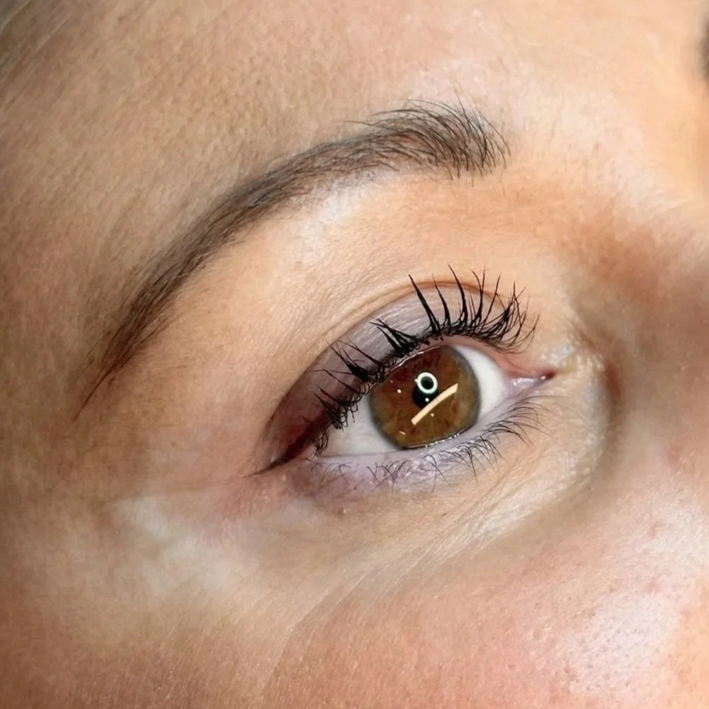 Close-up of a human eye with brown iris, long eyelashes, and well-groomed eyebrow.