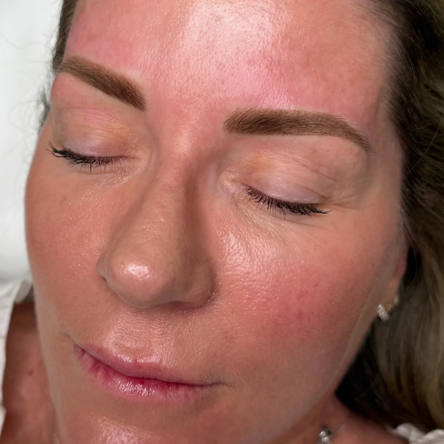 Close-up of a woman with well-groomed eyebrows and closed eyes.
