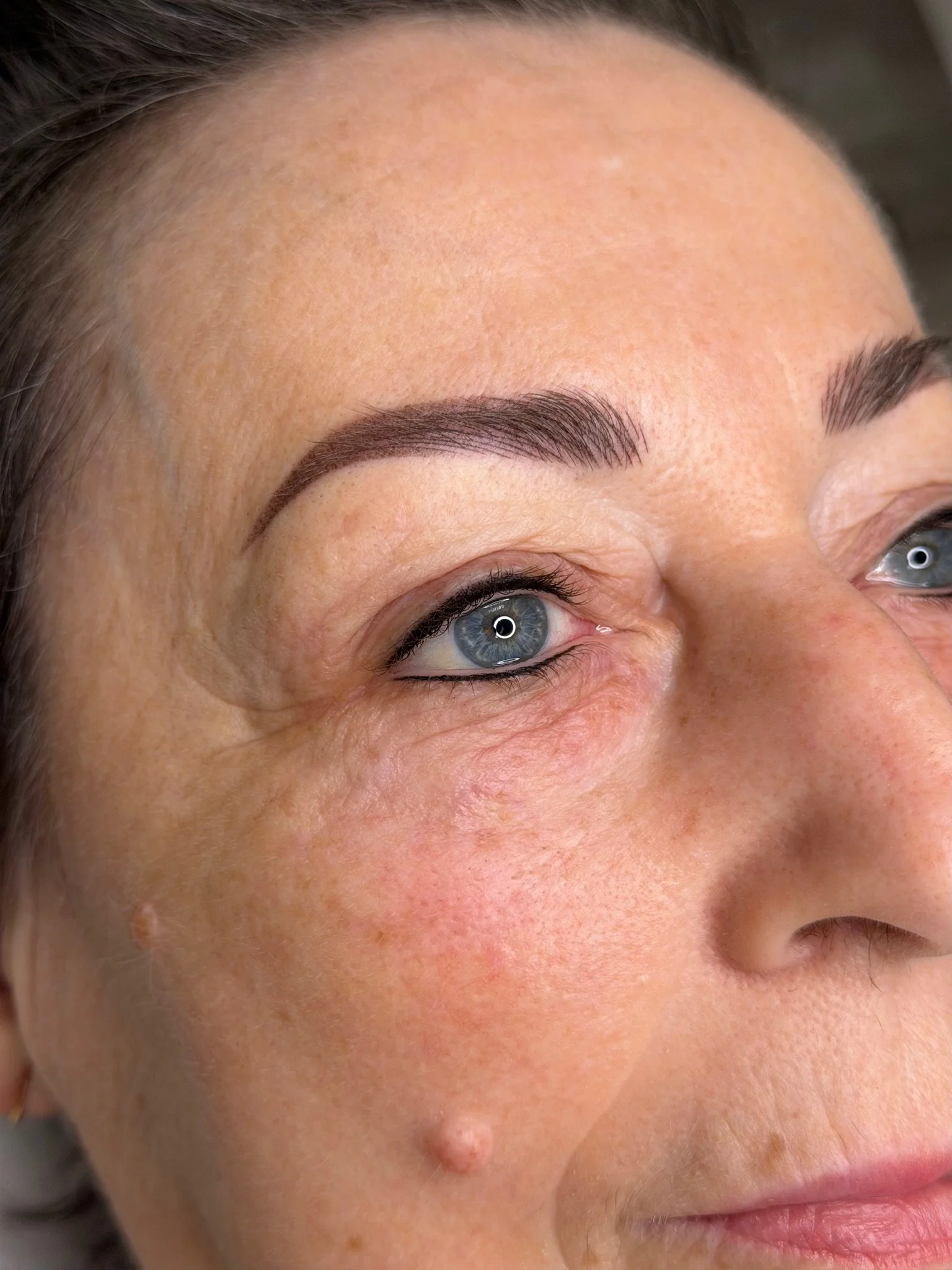 Close-up of a woman's face showing her forehead, eyebrows, and part of her eyes with clear skin and well-groomed eyebrows.