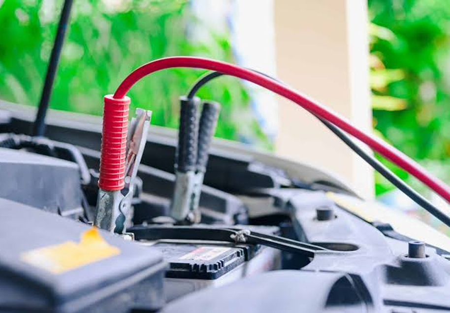 Car battery with red and black jumper cables connected