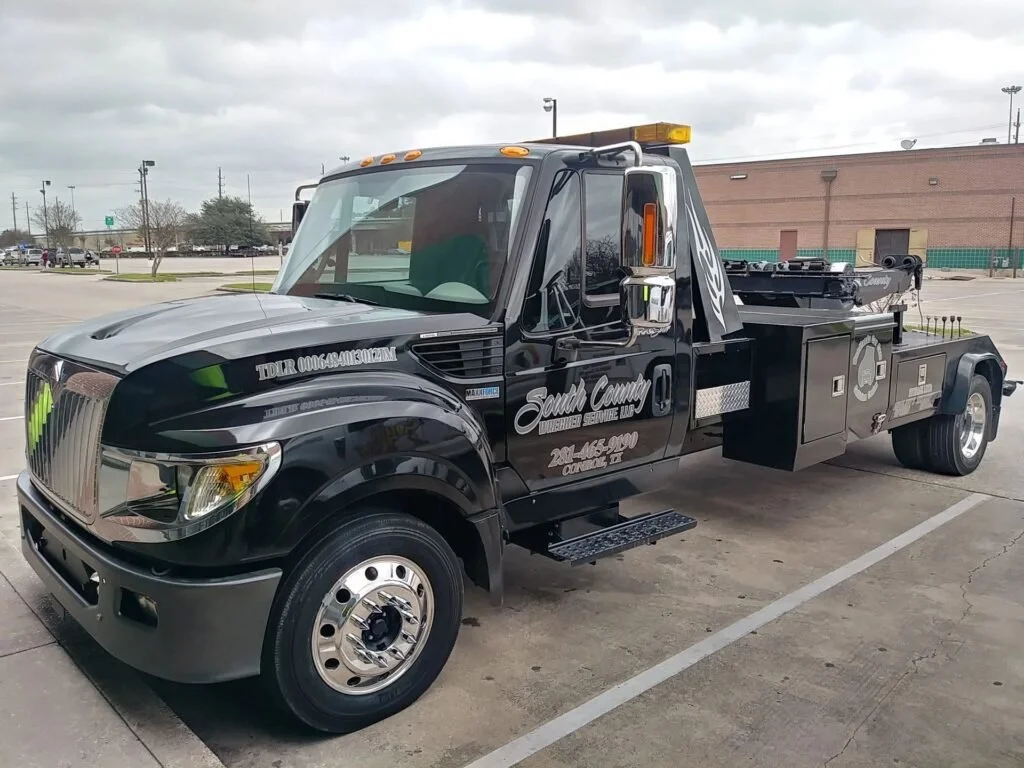 Black South County Towne Center Service Up tow truck parked in empty parking lot on cloudy day.