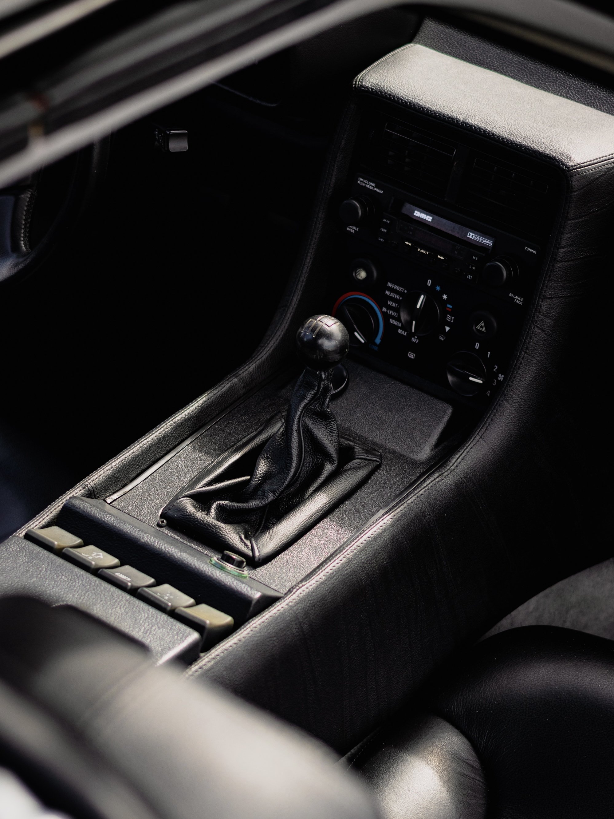 Interior of a car showing the gear shift, climate controls, and dashboard with a radio and vents.