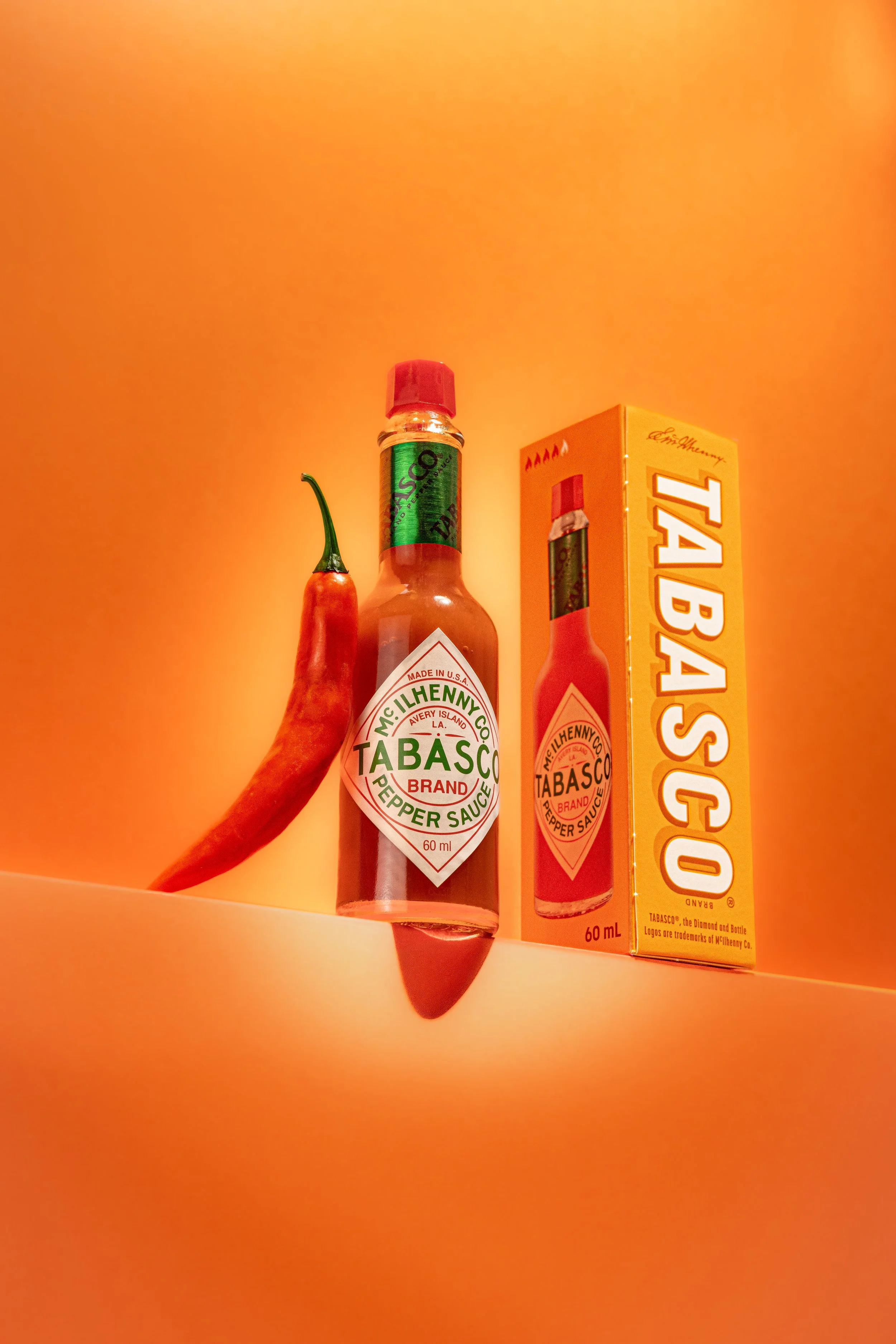 A product shoot of Tabasco hot sauce against an orange backdrop.