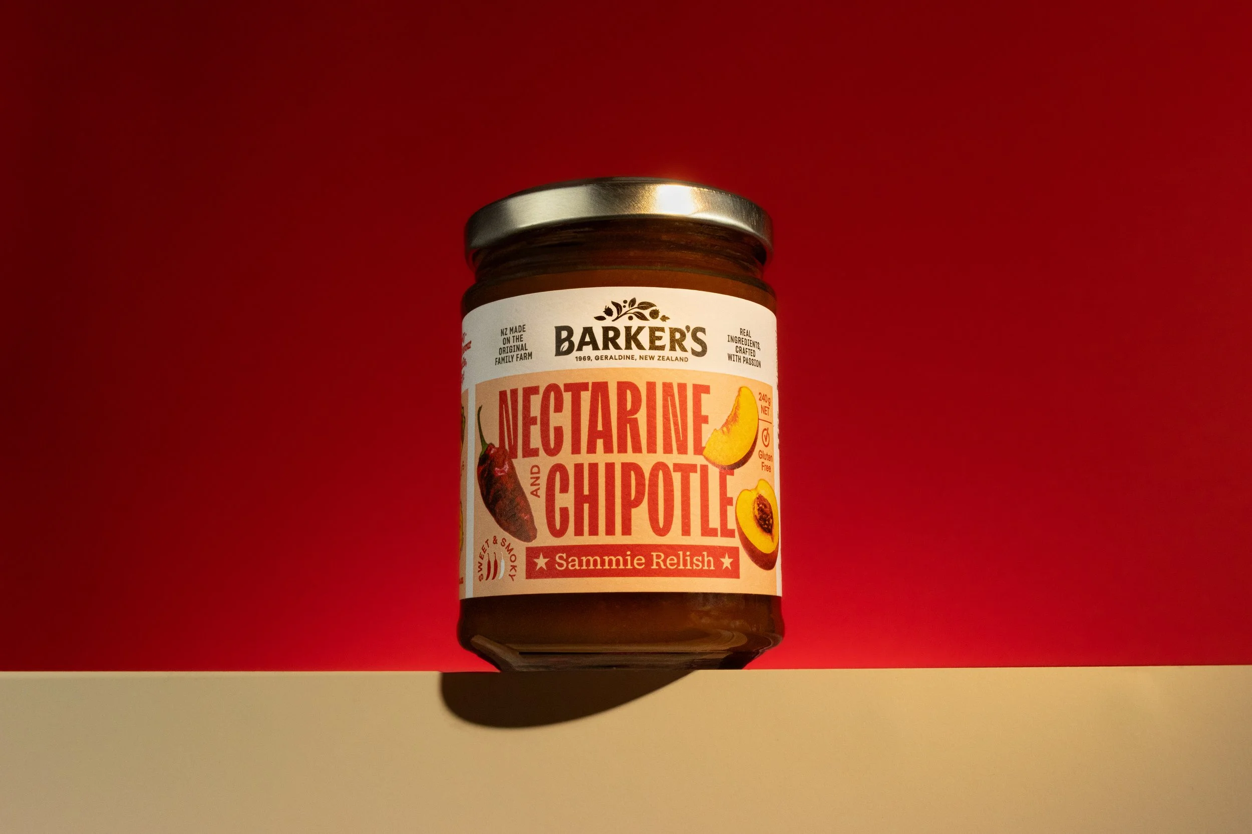 Product shoot for Barker's Nectarine and Chipotle Relish spread against a red & beige background.