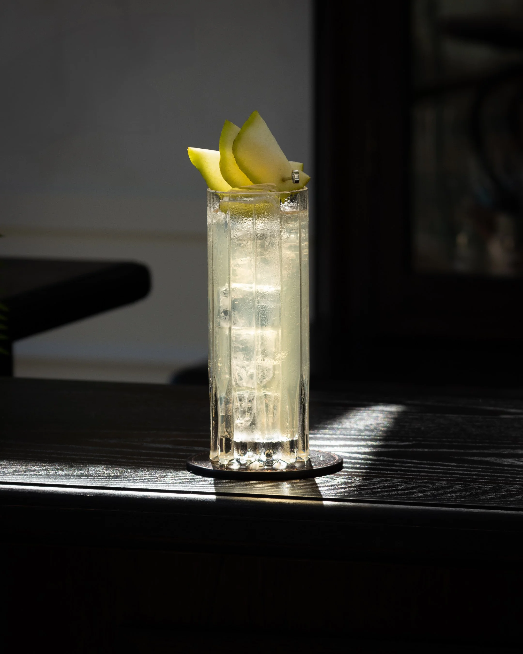 A highball cocktail garnished with a Pear fan & sitting in the sunlight, shot for a cocktail bar in the heart of Auckland CBD.