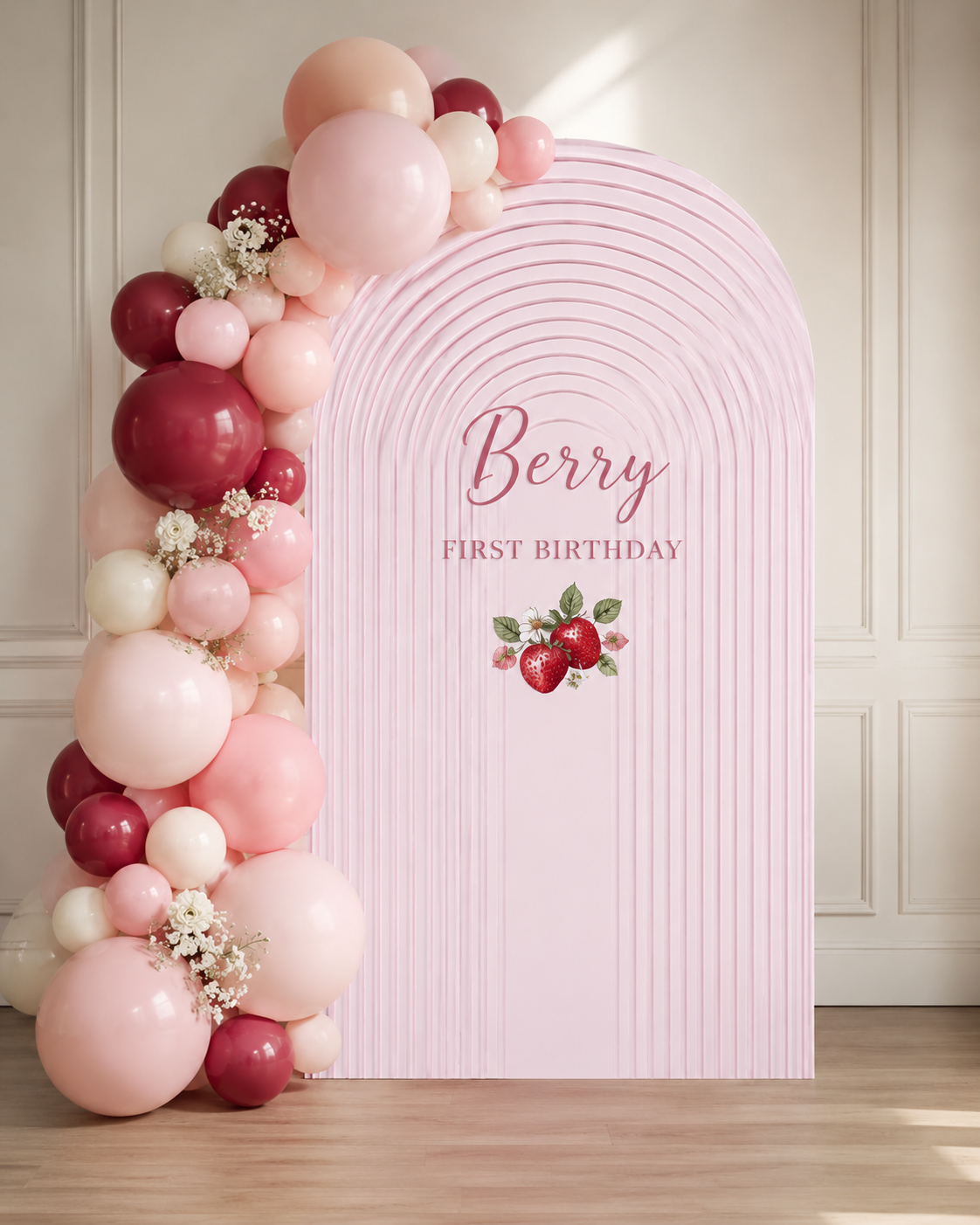 Pink and red balloons arranged along a pink striped backdrop with a strawberry illustration, displaying the wording "Berry First Birthday".