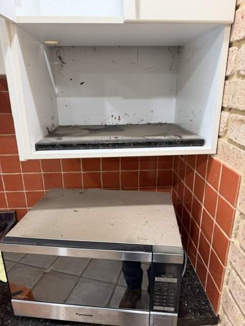 Microwave and cupboard before cleaning.