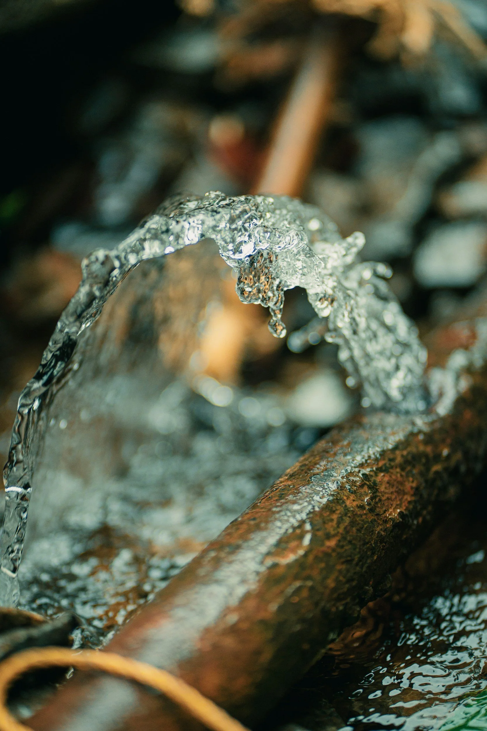 Close-up of an old copper pipe that has water leaking from it and in need of repair