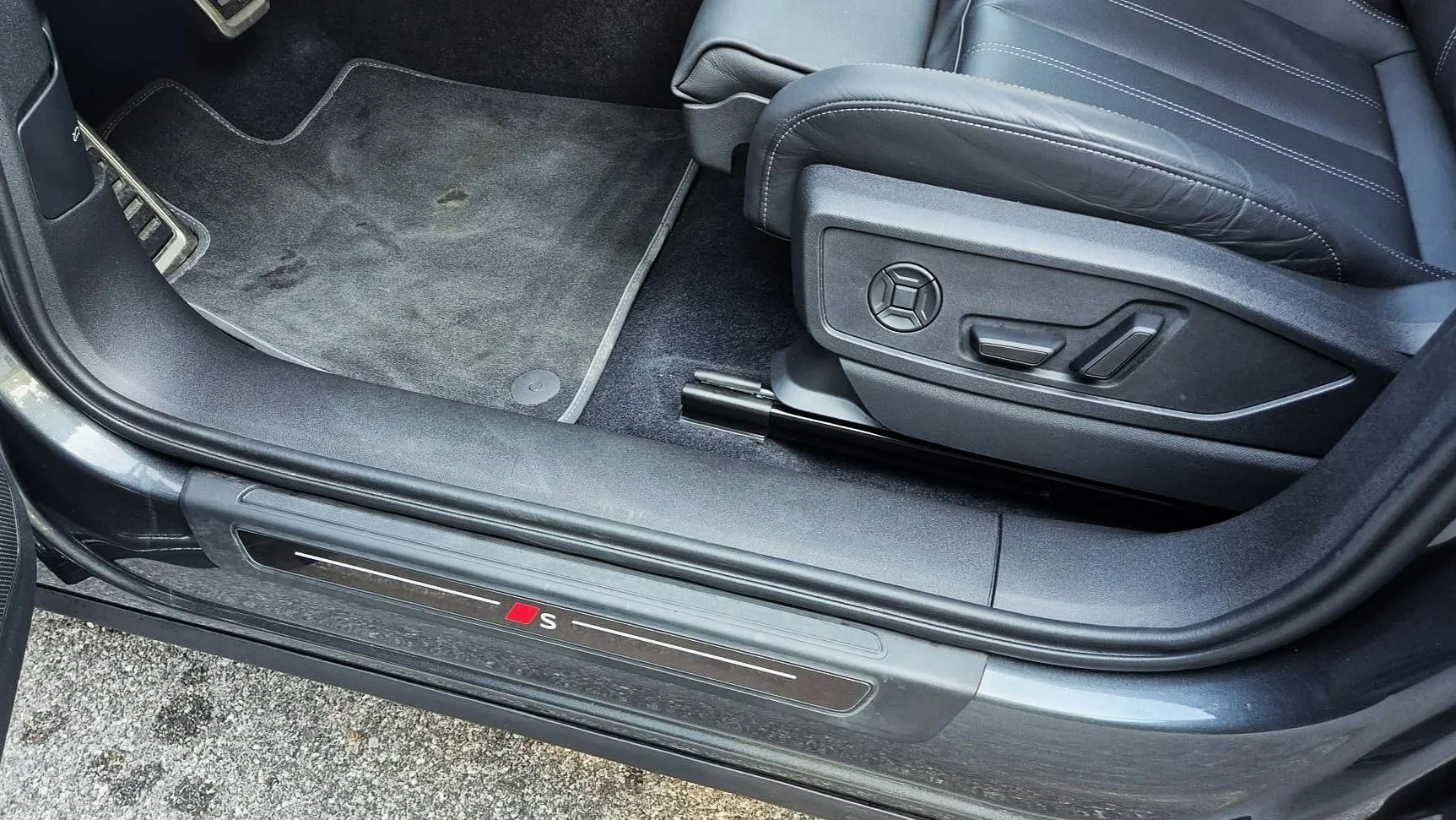 Audi Q5 Interno di un'auto sportiva con sedile regolabile, tappetino e soglia con logo 'S' rossa.