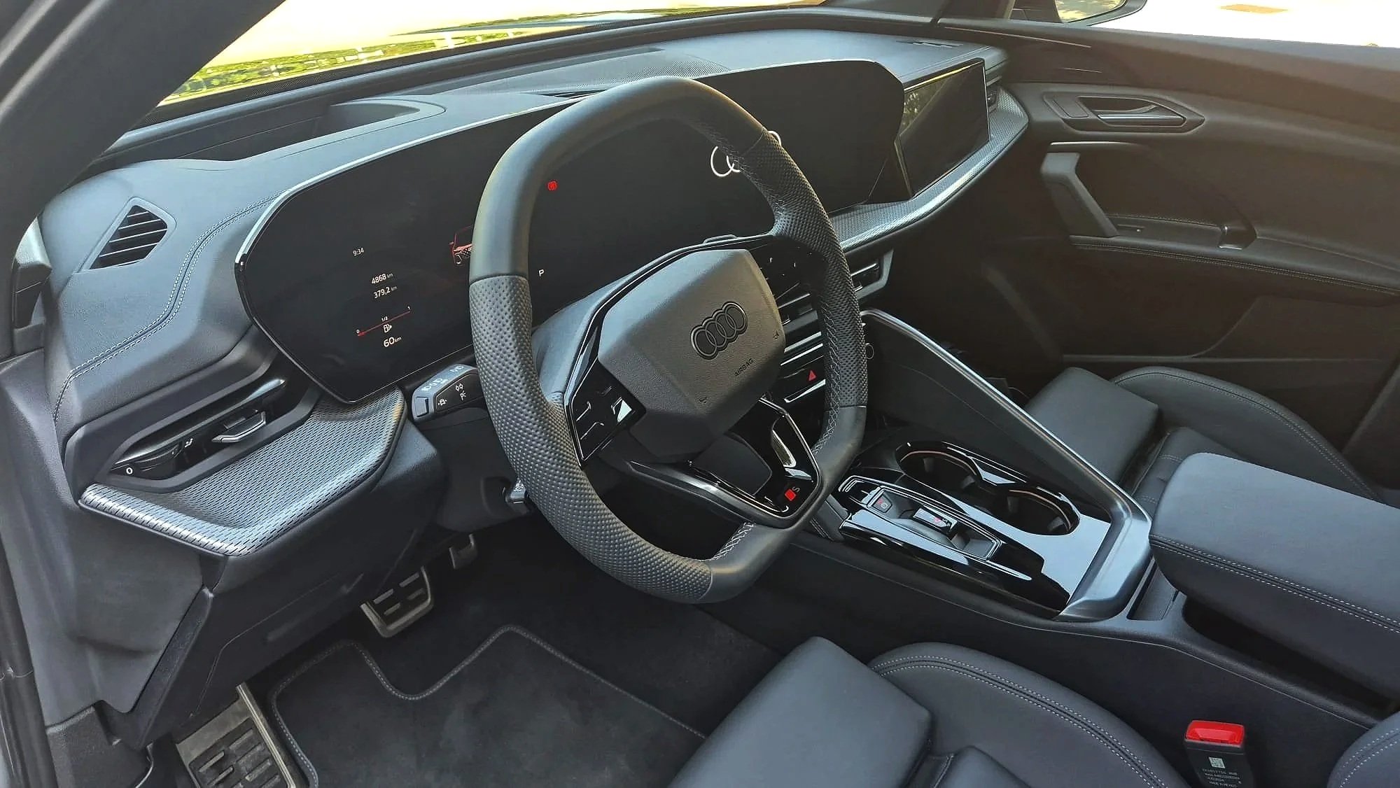 Audu Q5 Interno di un'auto di lusso con volante, display digitale e sedili in pelle.