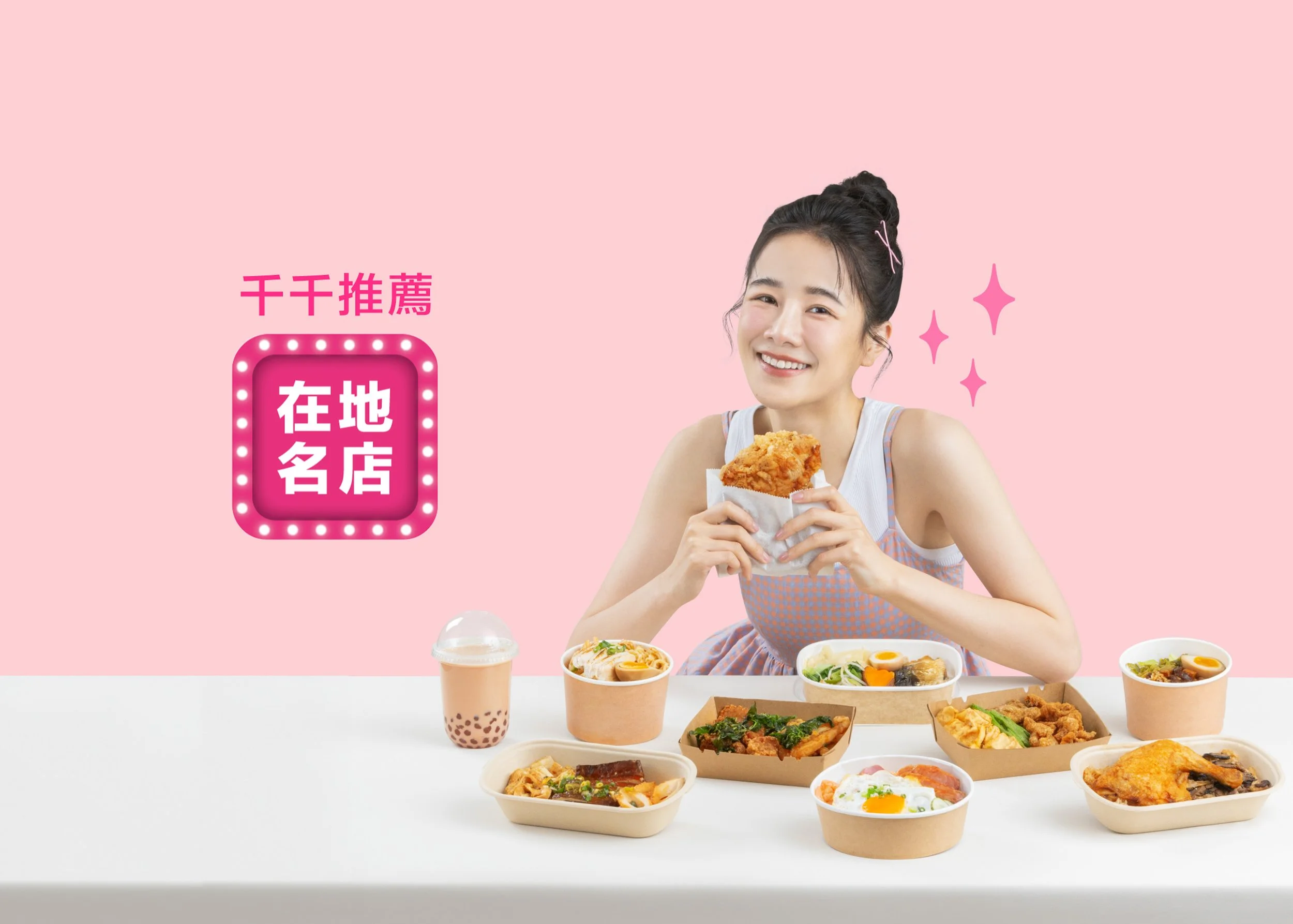 A young woman with dark hair in a bun, smiling and holding a piece of fried chicken, sitting at a table filled with various Asian dishes such as ramen, salad, and rice bowls, with a pink background and pink stars on the right side.