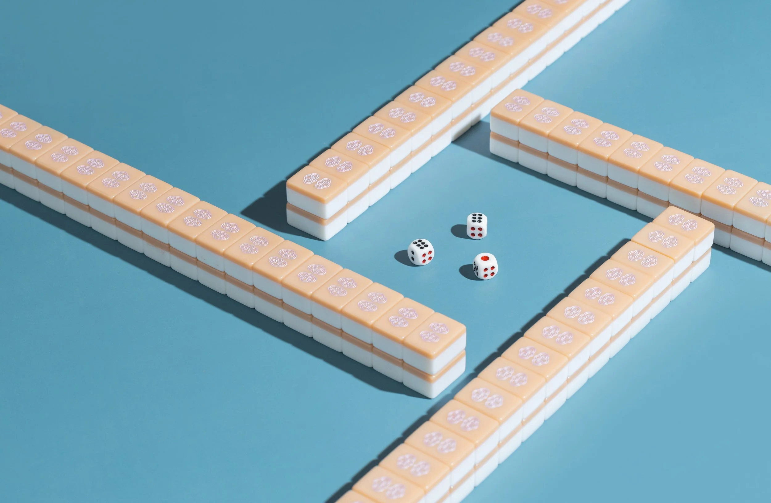 A game of Mahjong featuring a close-up of the tiles, with three dice placed in the center on a blue minimalistic surface.