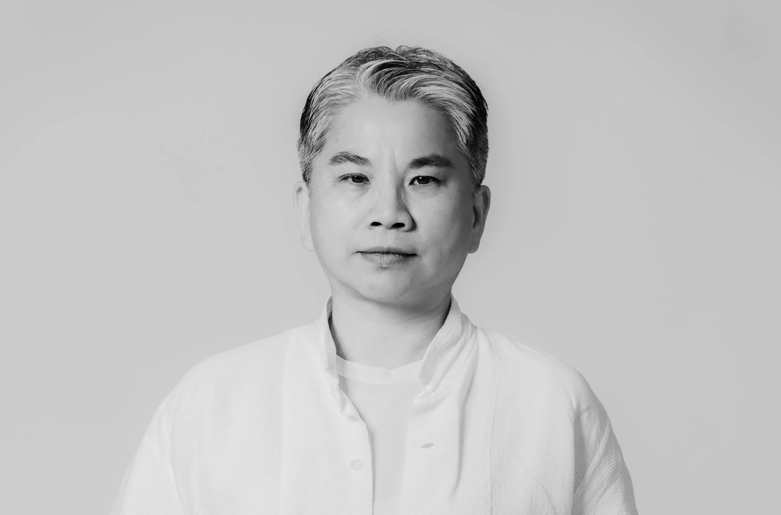 Black and white portrait of a woman with short, combed-back hair, wearing a high-collared shirt.
