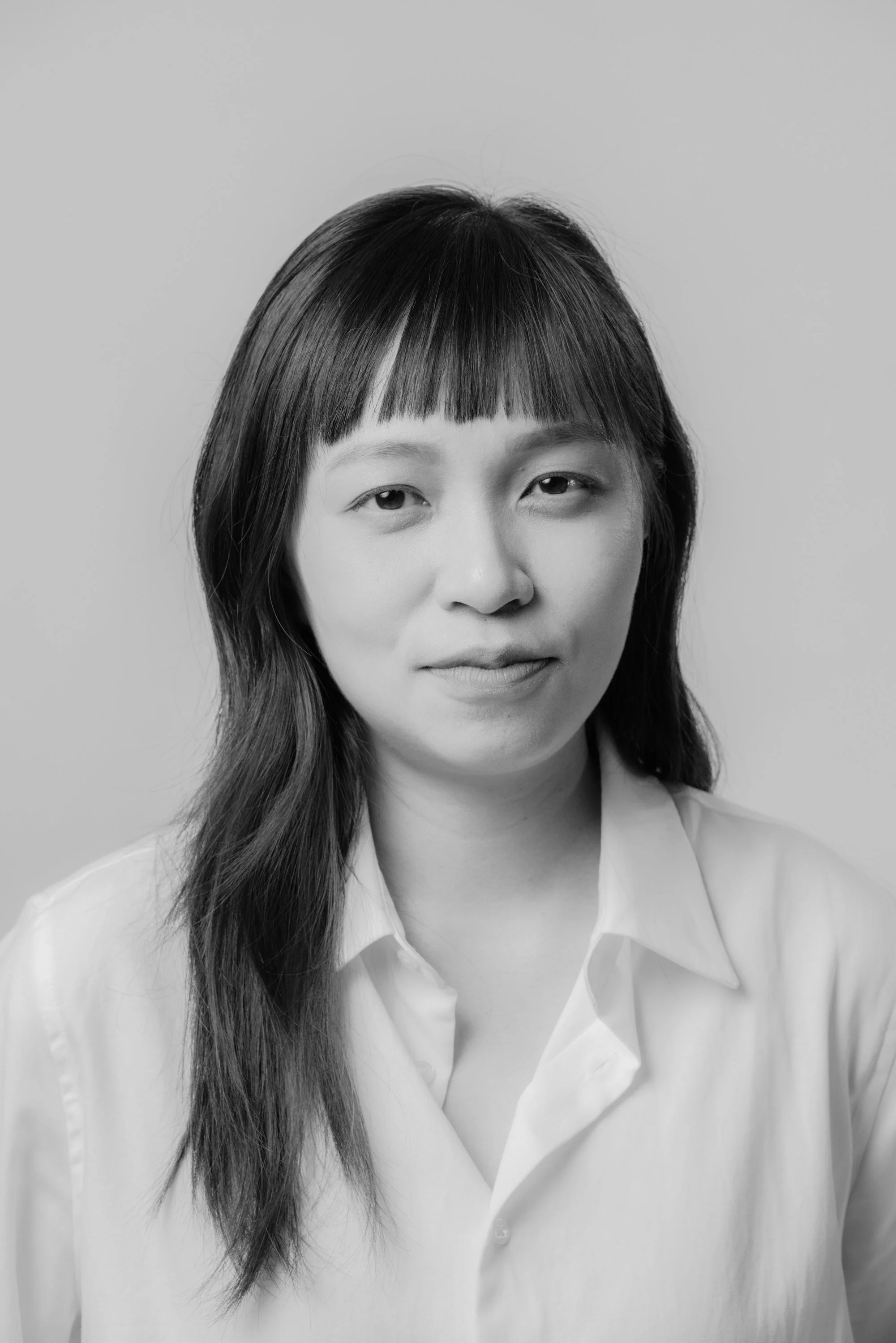 Black and white portrait of a woman with long dark hair, wearing a collared shirt.