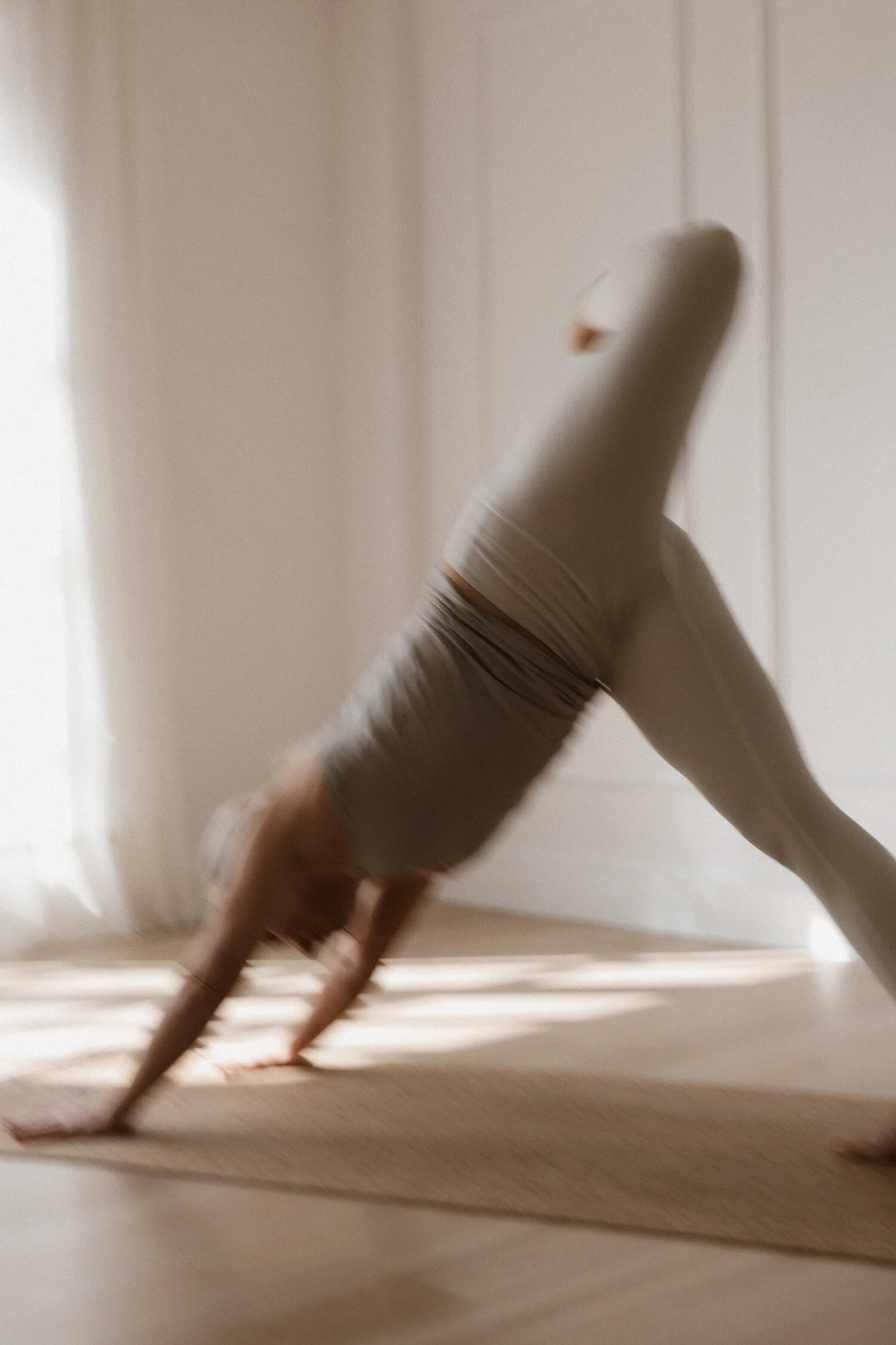Person macht Yogaübung auf dem Boden in einem Raum mit weißer Wand, die Bewegung ist unscharf und gewellte