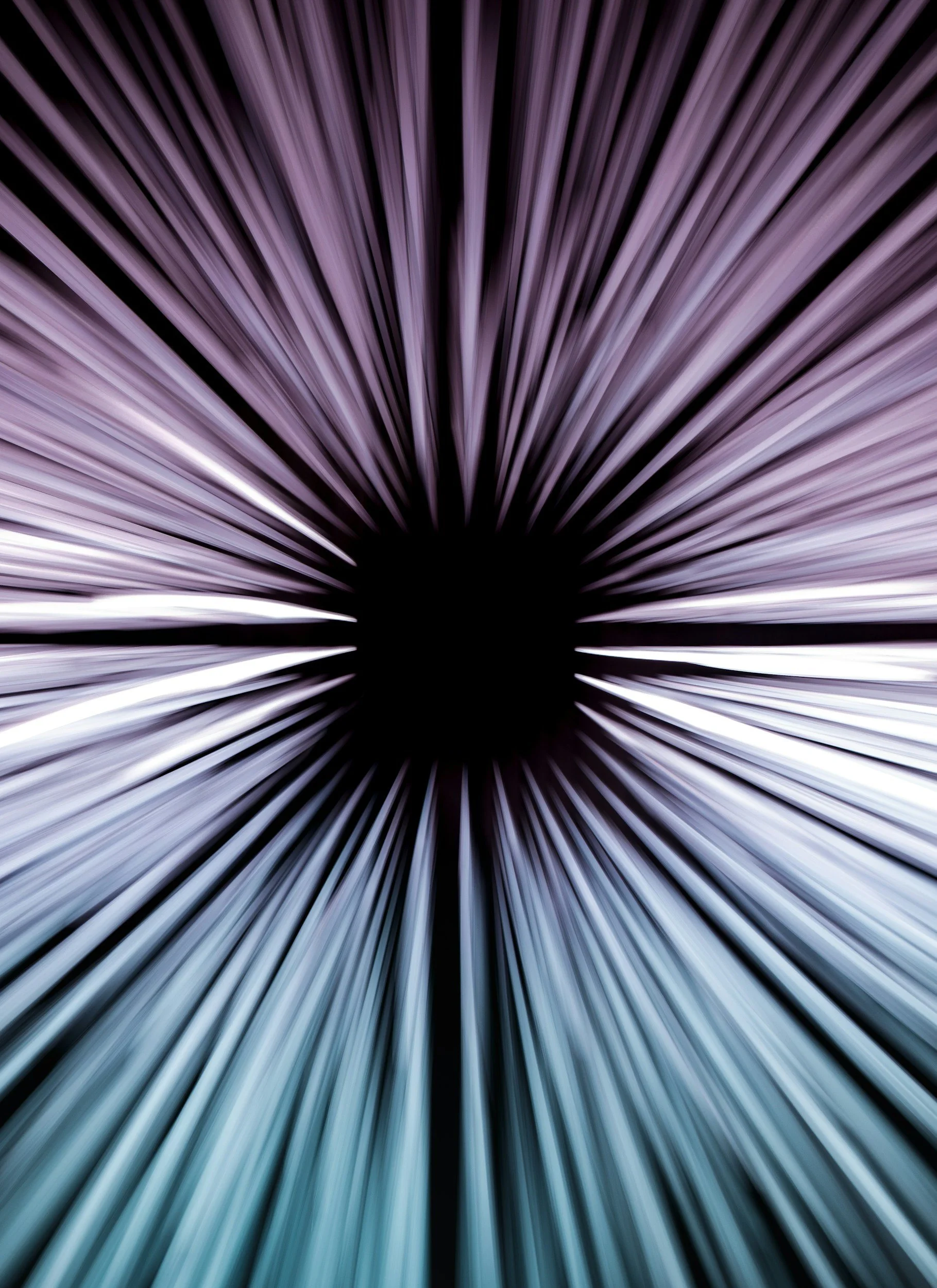Long exposure photograph of light trails radiating outward in shades of purple, white, and blue from a dark central point.