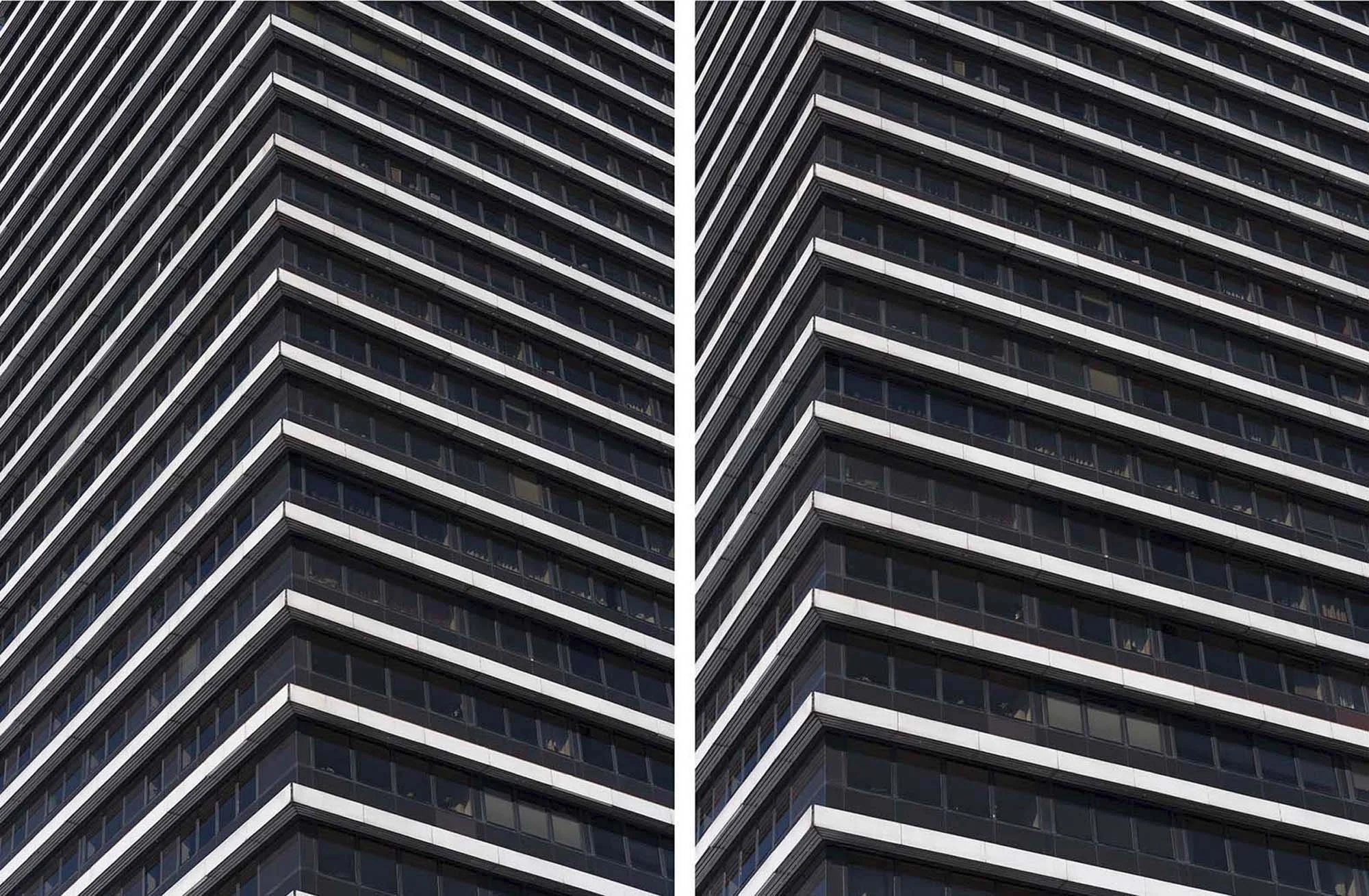 Hochhausfassade mit mehreren Stockwerken und reflektierenden Fenstern, aufgenommen von unten nach oben.