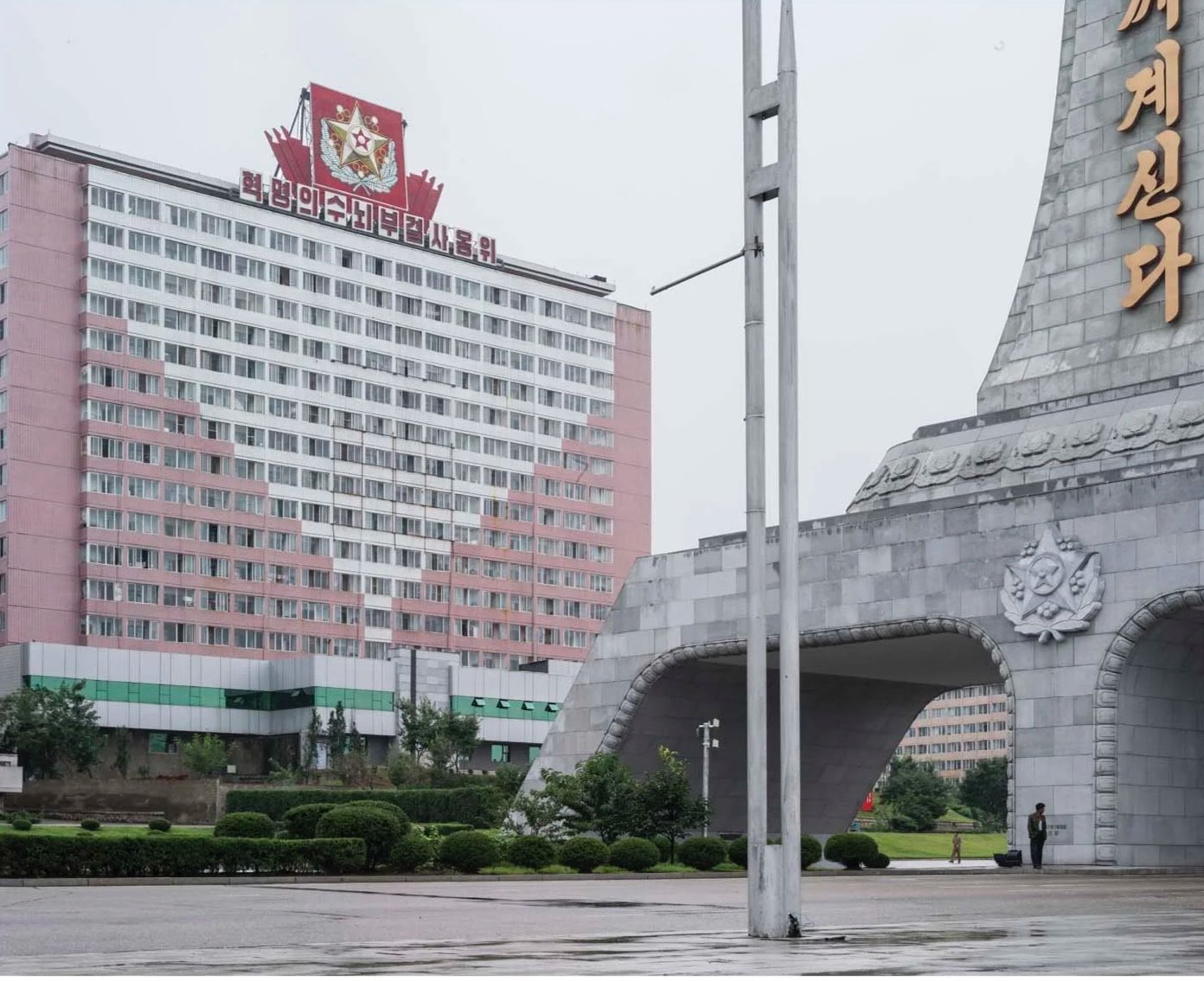 Pjöngjang, Nordkorea: Monument des ewigen Lebens für Kim Il-sung an der Kumsong-Straße. Durch die monumentalen Torbögen führt die Straße zum Kumsusan-Palast der Sonne, dem Mausoleum von Kim Il-sung und Kim Jong-il. Verwaltungsgebäude im Hintergrund.