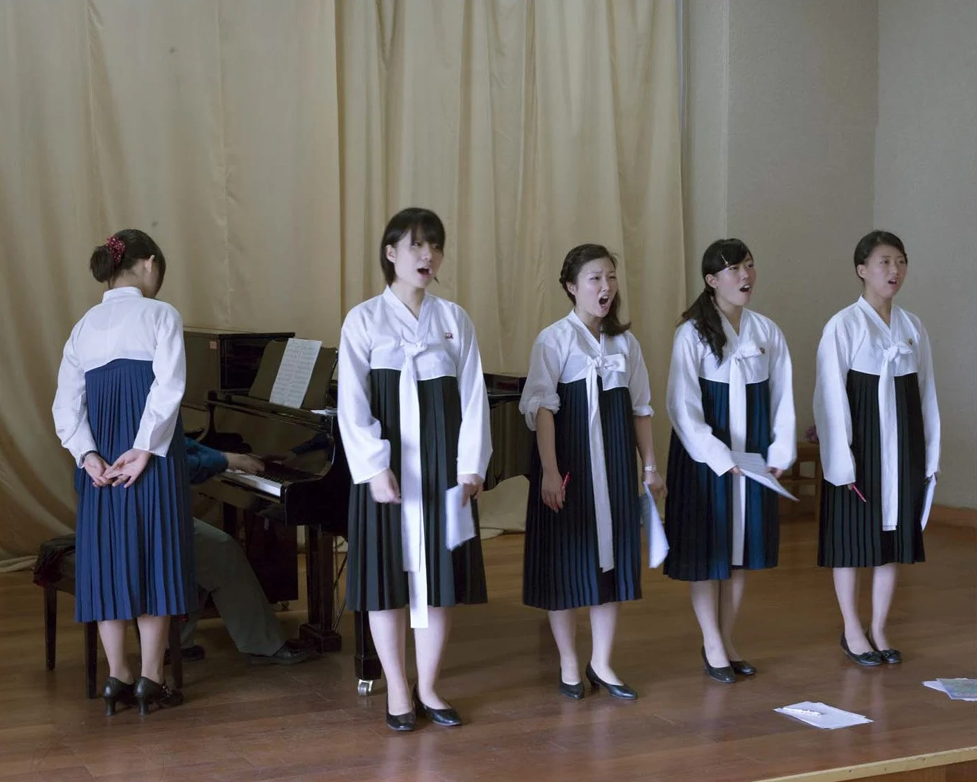 Mädchenchor im Schülerpalast Mangyongdae in Pjöngjang, Nordkorea: Junge Sängerinnen in traditioneller nordkoreanischer Kleidung (Joseon-ot / Hanbok) singen während einer Musikstunde, begleitet von einem Klavier. Der Schülerpalast ist eine zentrale Ei