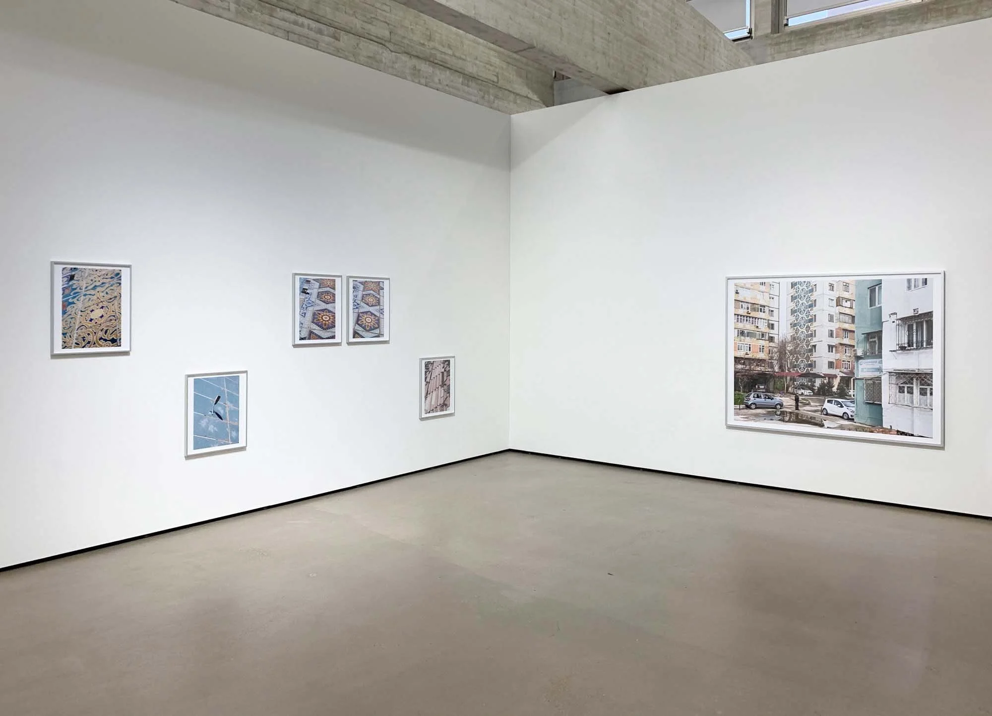 Bilder in einem Kunstmuseum, weiße Wände mit Kunstwerken und große Fenster, die Tageslicht eindringen lassen.