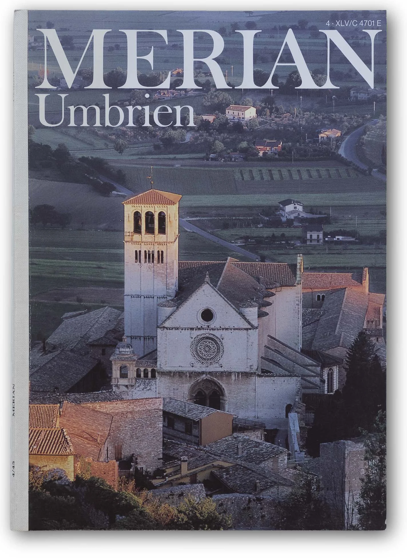 Die Titelseite einer Zeitschrift mit dem Titel 'MERIAN Umbriën', die eine Landschaft mit einer Kirche und Hügeln in Umbrien, Italien, zeigt.