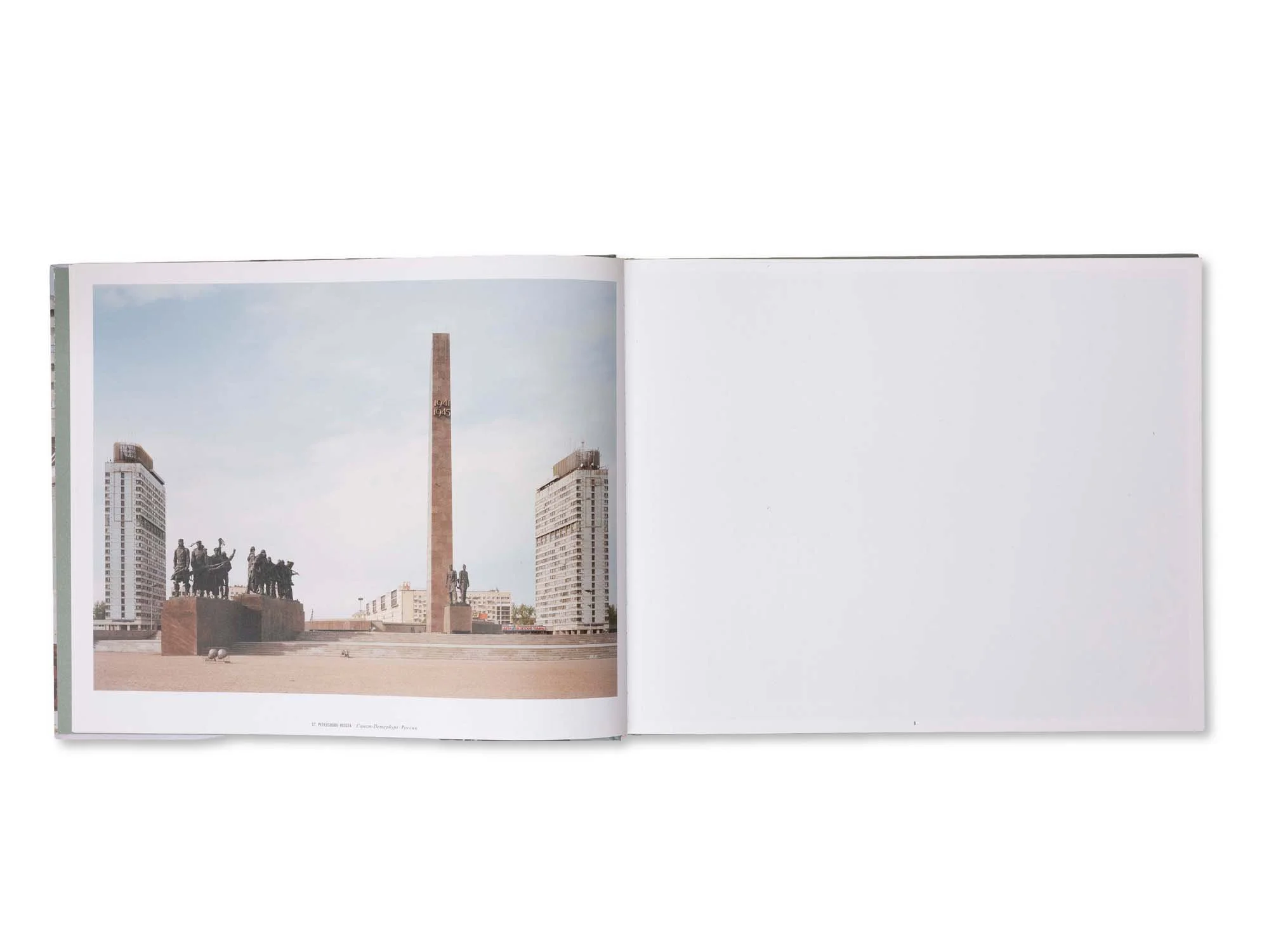 Offene Buchseite mit Fotografie einer Stadt mit Hochhäusern, einem Obelisken in der Mitte und einer Statue im Vordergrund.