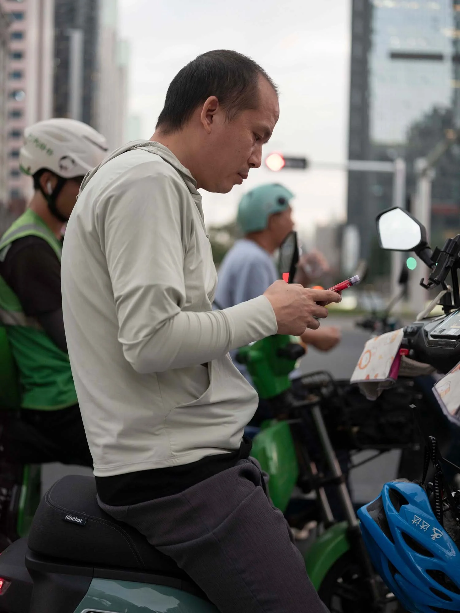 Documentary photograph by Roman Bezjak highlighting Shenzhen as a global leader in e-mobility, showing residents, families, and delivery workers navigating the city on electric scooters.