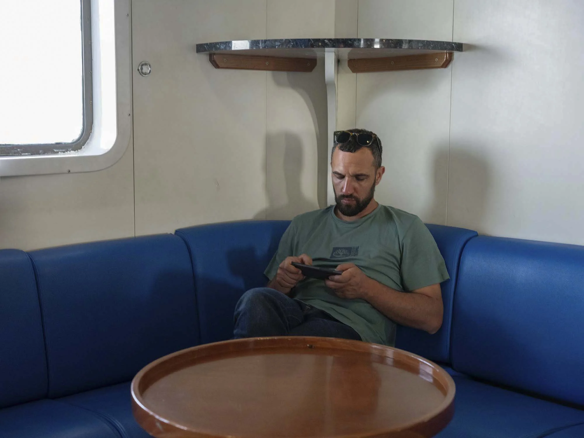 Commuters on the early morning ferry from Split to Brač, Croatia, resting and using smartphones on the deck, documentary photography by Roman Bezjak