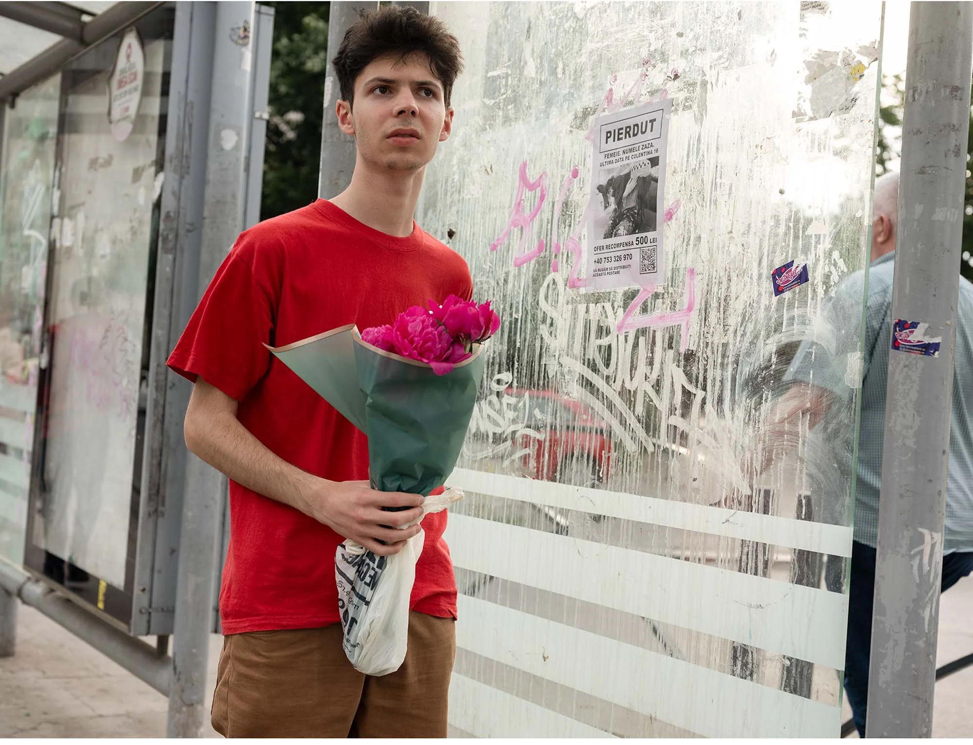 Documentary photo by Roman Bezjak from the series "Bucharest Tram," showing commuters waiting at Piața Unirii, young man with flowers
