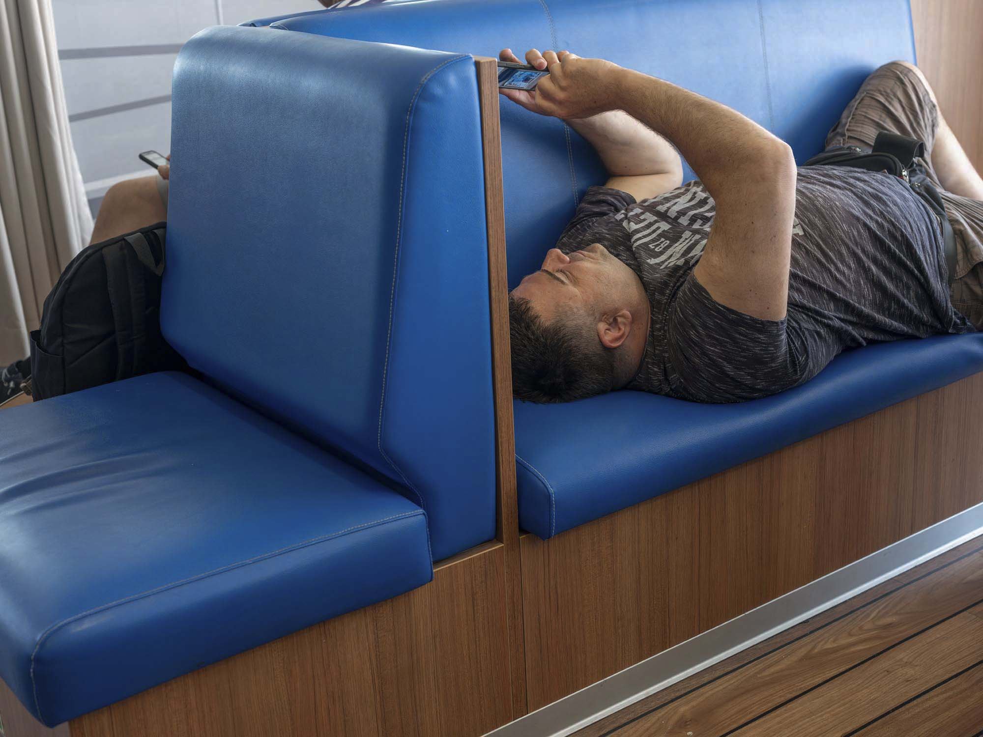 Commuters on the early morning ferry from Split to Brač, Croatia, resting and using smartphones on the deck, documentary photography by Roman Bezjak