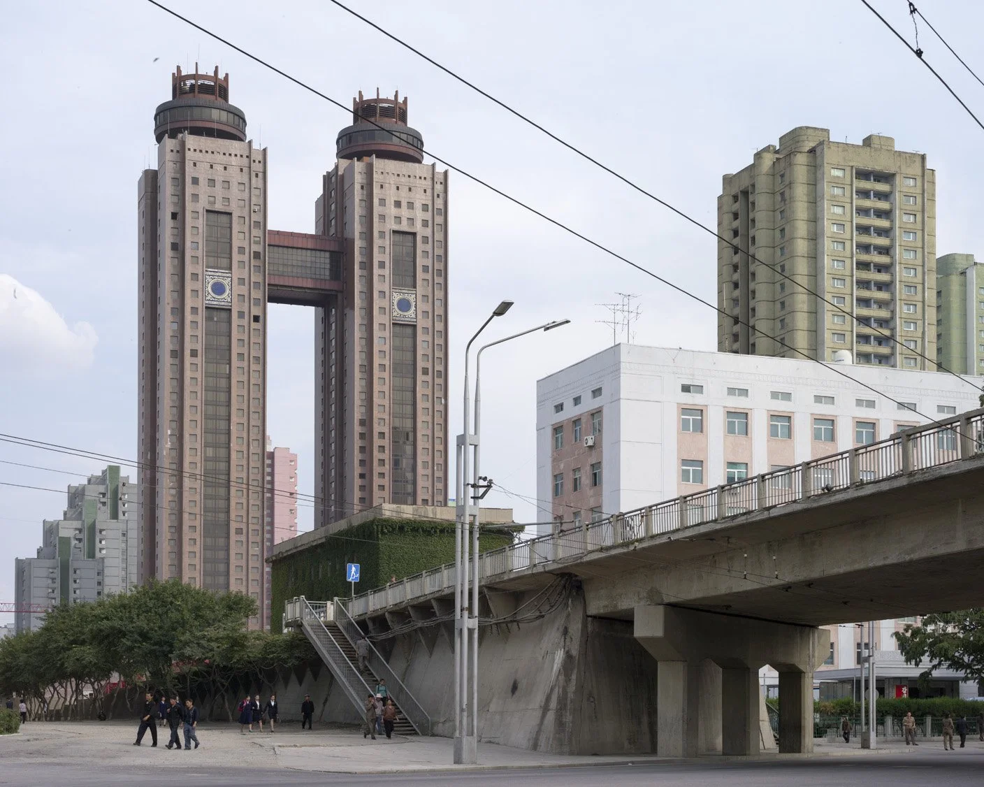 Koryo Hotel in Pjöngjang, Nordkorea: Die charakteristischen Zwillingstürme des weltbekannten Luxushotels prägen das Stadtbild im Bezirk Chung-guyŏk. Eine Straßenüberführung führt im Vordergrund an der eindrucksvollen brutalistischen Architektur des 1