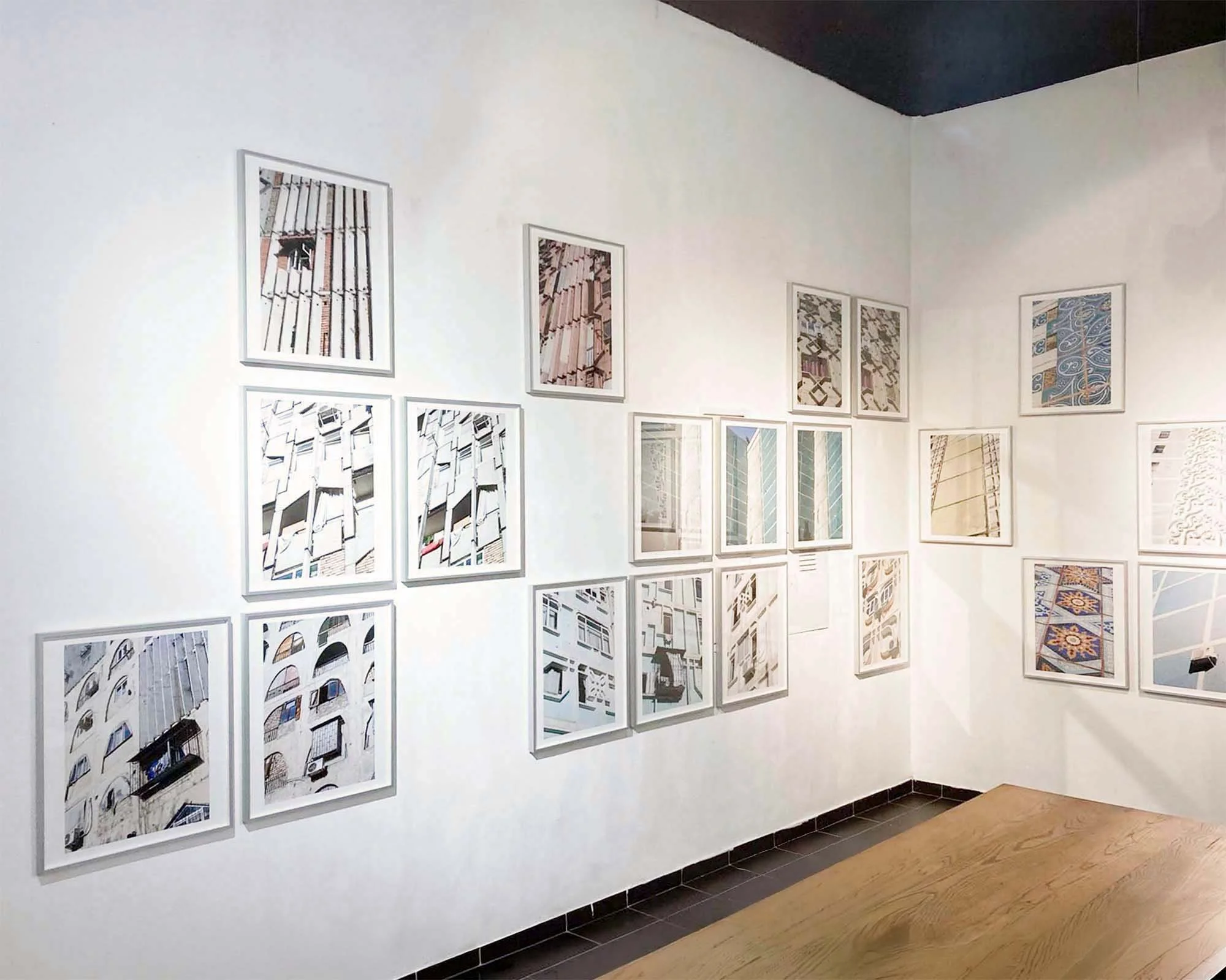 Eine Wand in einer Galerie mit mehreren gerahmten Kunstdrucken, die verschiedene Architektur- und Stadtansichten zeigen.
