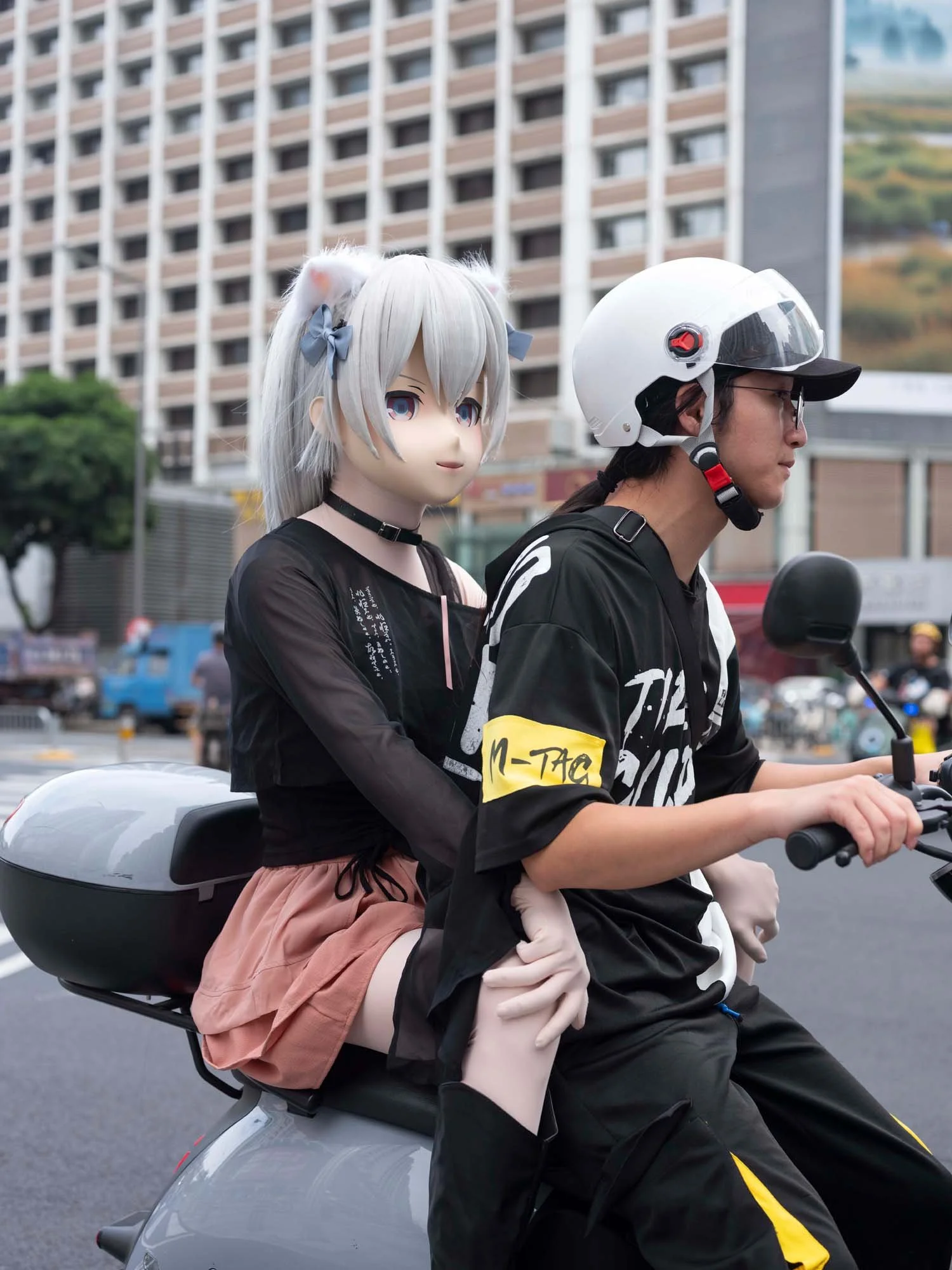 Documentary photograph by Roman Bezjak highlighting Shenzhen as a global leader in e-mobility, showing residents, families, and delivery workers navigating the city on electric scooters. young woman with a mask