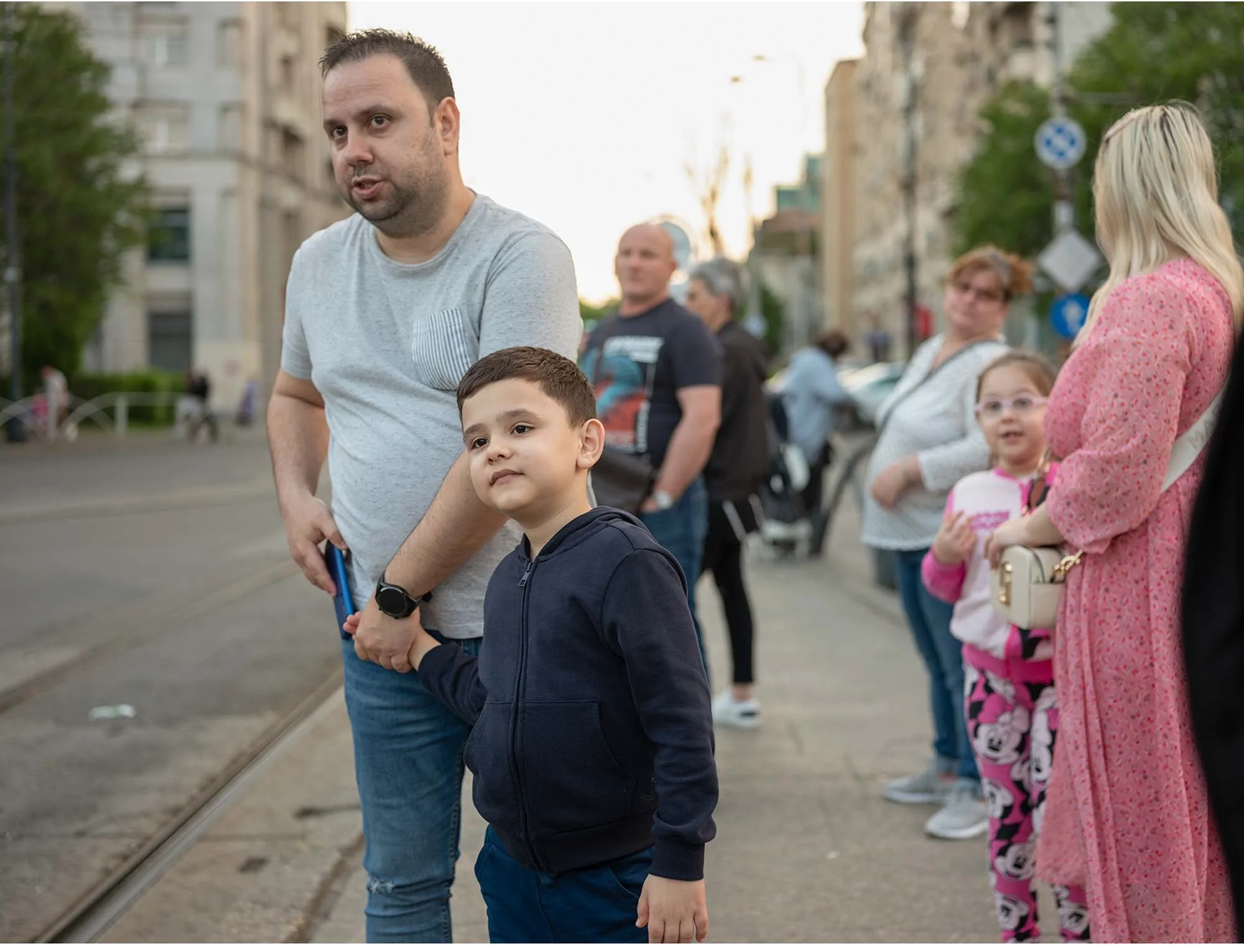 Documentary photo by Roman Bezjak from the series "Bucharest Tram," showing commuters waiting at Piața Unirii, father and son