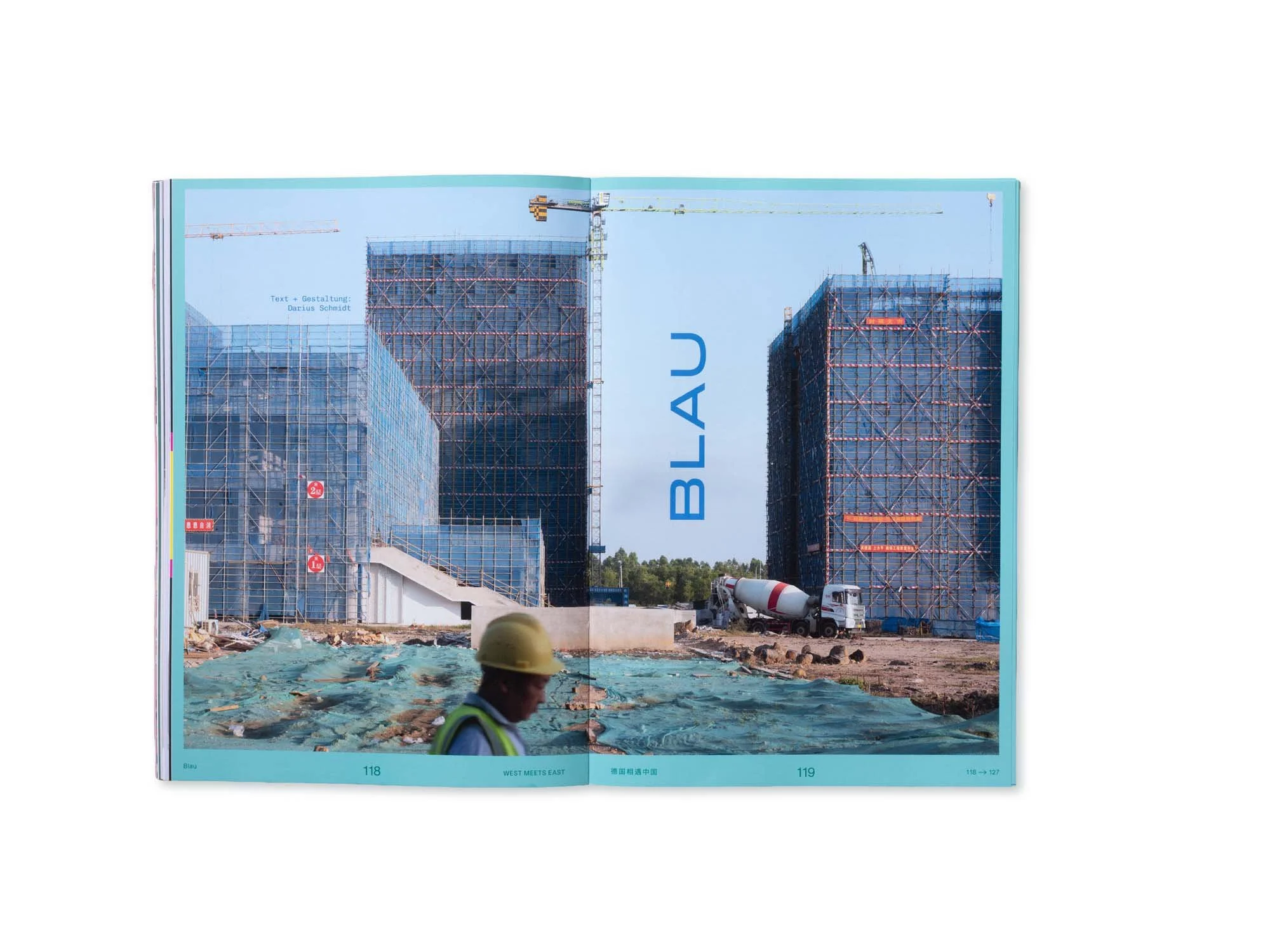 Blick auf eine Baustelle mit mehreren Hochhäusern im Bau, Baugerüsten und Baukränen, im Vordergrund eine Person mit Schutzhelm.
