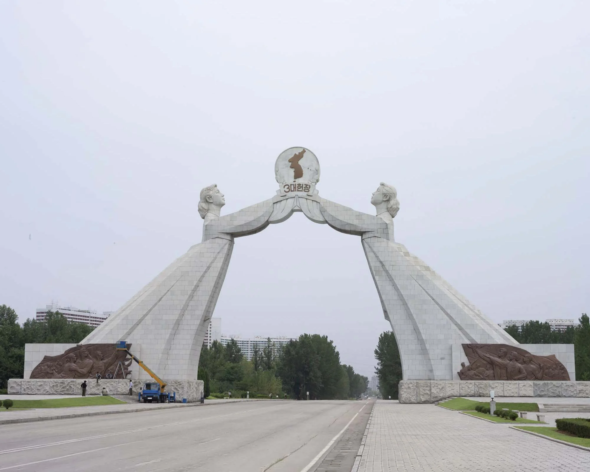 Denkmal für die Wiedervereinigung (Bogen der Wiedervereinigung) in Pjöngjang, Nordkorea: Der imposante Monumentalbogen überspannt die Autobahn der Wiedervereinigung am südlichen Stadteingang. Zwei Frauen in traditioneller koreanischer Kleidung repräs