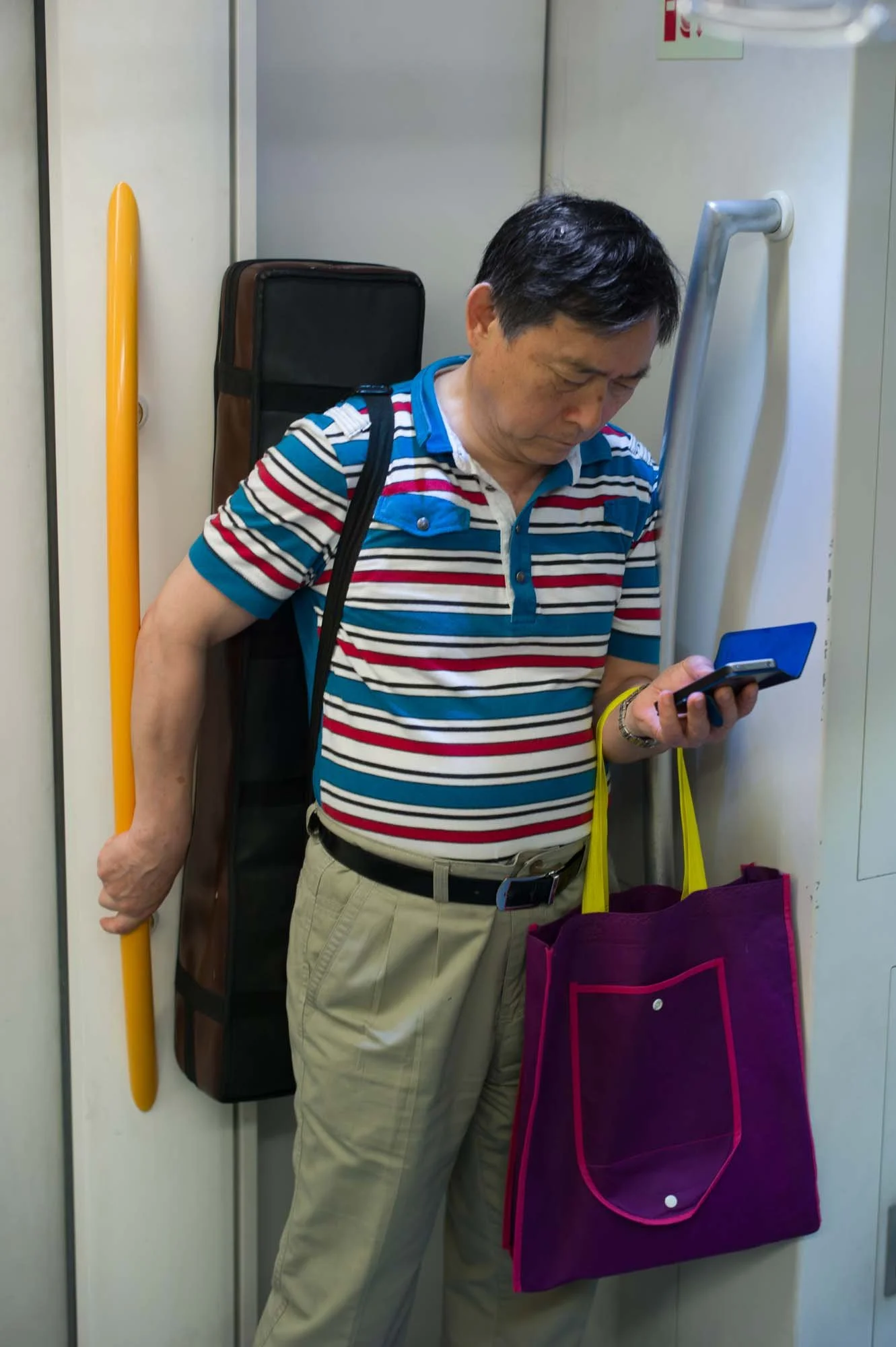 Submerged in thought, passengers in a Shanghai subway car gaze into their smartphones, photographed by Roman Bezjak