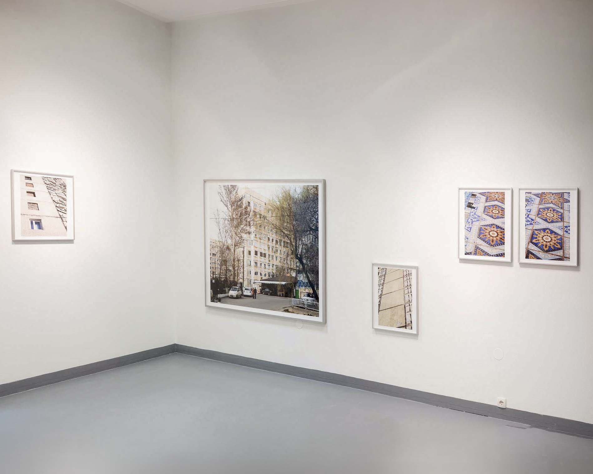 Bilder in einem weißen Kunstraum, einige zeigen Gebäude und Straßen, andere Muster und Designs.