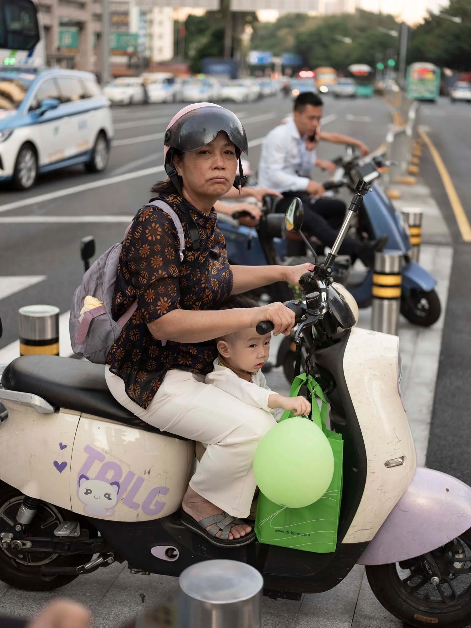 Documentary photograph by Roman Bezjak highlighting Shenzhen as a global leader in e-mobility, showing residents, families, and delivery workers navigating the city on electric scooters.