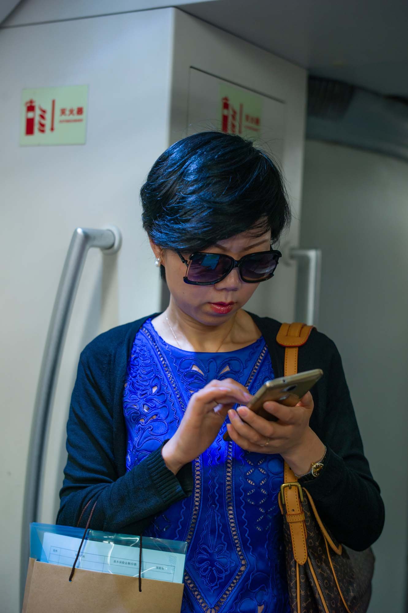 Submerged in thought, passengers in a Shanghai subway car gaze into their smartphones, photographed by Roman Bezjak