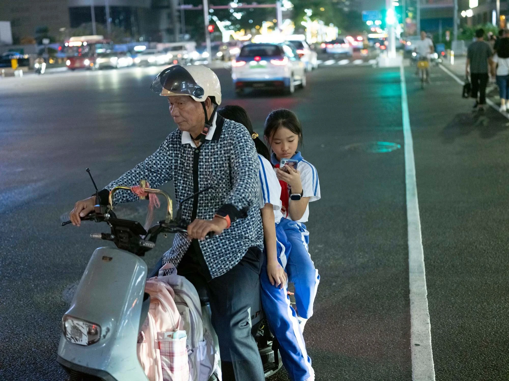 Documentary photograph by Roman Bezjak highlighting Shenzhen as a global leader in e-mobility, showing residents, families, and delivery workers navigating the city on electric scooters.