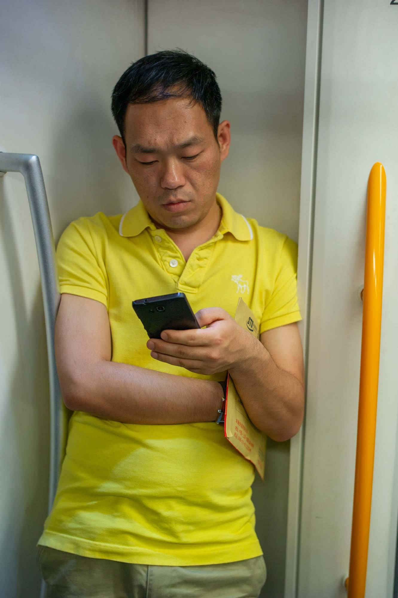 Submerged in thought, passengers in a Shanghai subway car gaze into their smartphones, photographed by Roman Bezjak