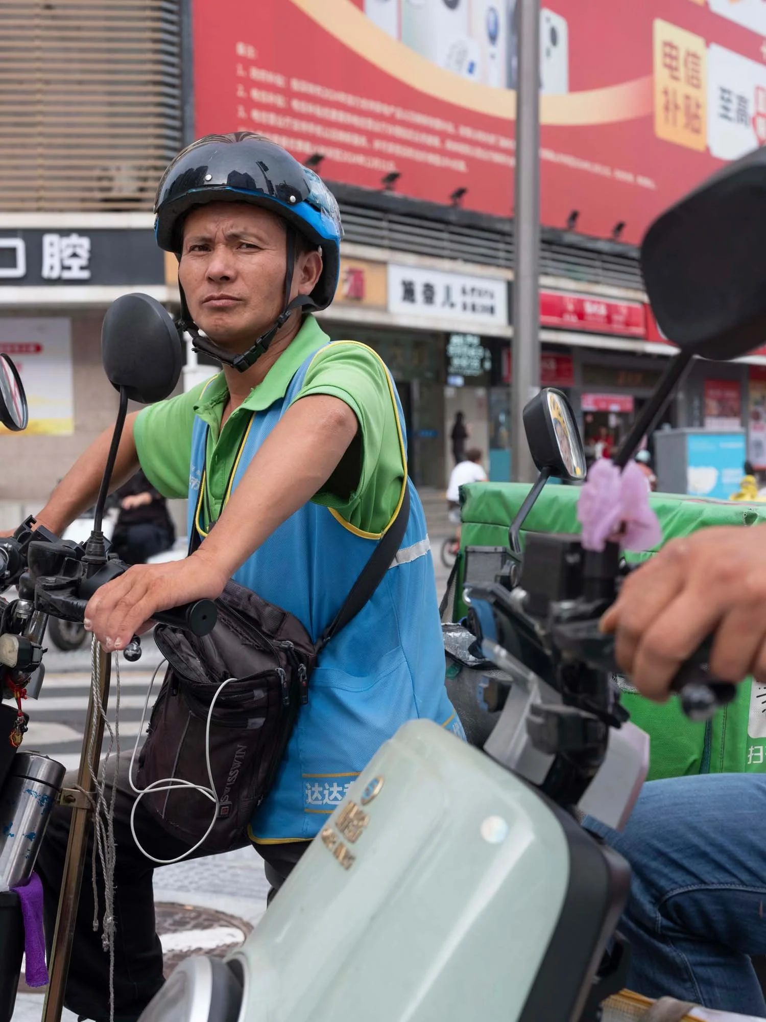 Documentary photograph by Roman Bezjak highlighting Shenzhen as a global leader in e-mobility, showing residents, families, and delivery workers navigating the city on electric scooters.
