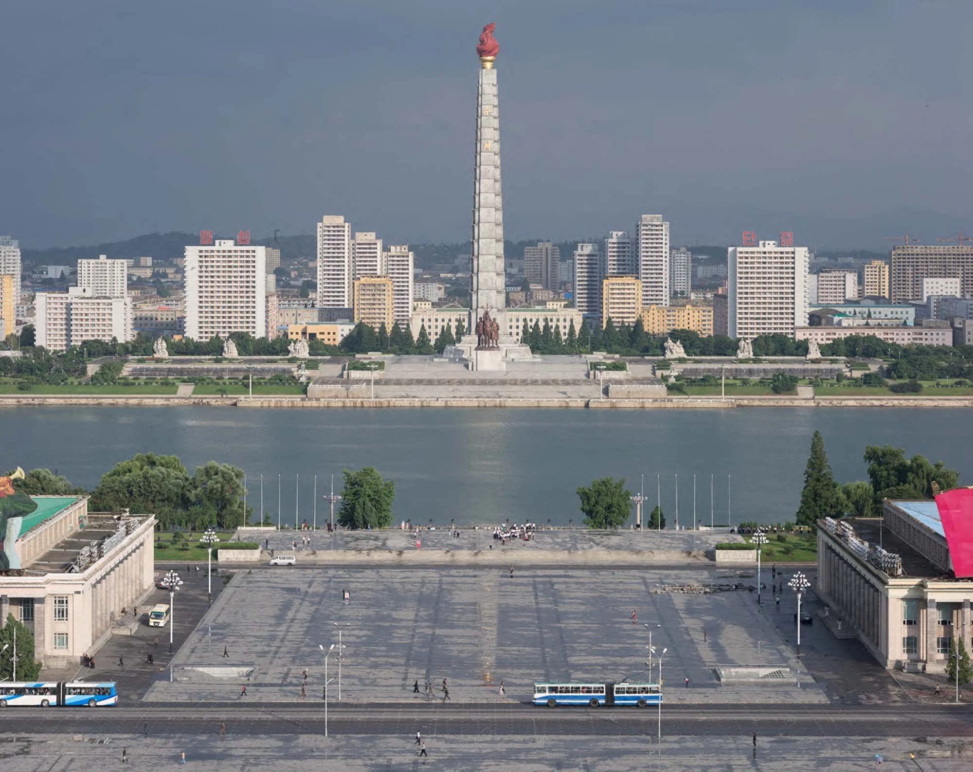 Kim-Il-sung-Platz und Juche-Turm am Taedong-Fluss in Pjöngjang, Nordkorea: Der Blick vom Großen Palast der Volksstudien führt über den weitläufigen Kim-Il-sung-Platz und den Taedong-Fluss hinüber zum 170 Meter hohen Turm der Juche-Ideologie. Das Monu