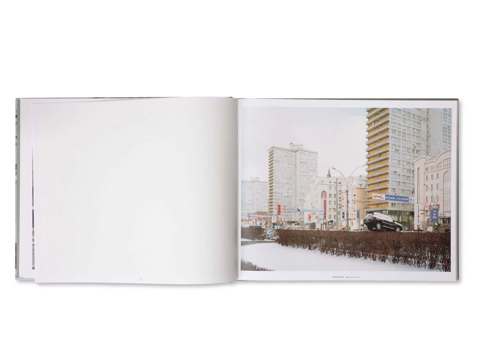 Offenbares Buch mit einer Stadtaufnahme, die hohe Gebäude, Werbeschilder und Autos zeigt, im Winter mit verschneitem Boden.