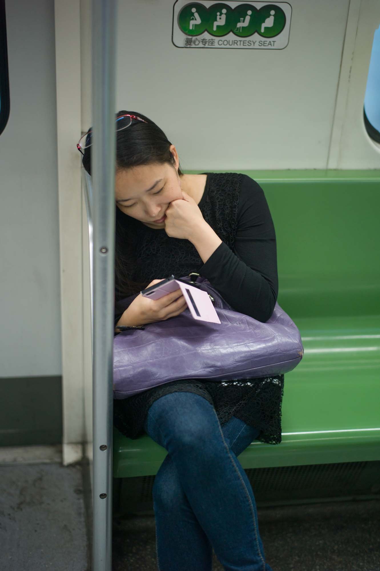 Submerged in thought, passengers in a Shanghai subway car gaze into their smartphones, photographed by Roman Bezjak