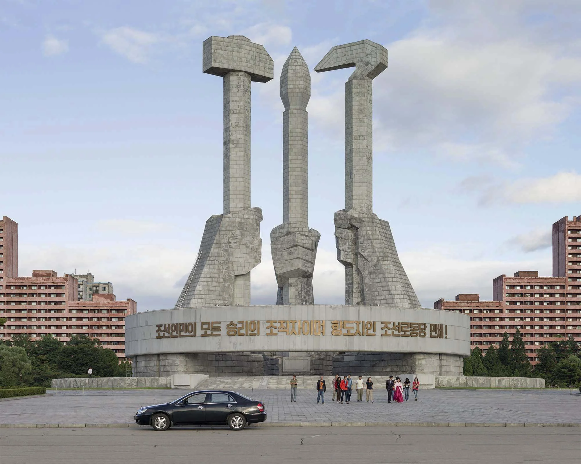 Denkmal zur Gründung der Partei der Arbeit Koreas in Pjöngjang, Nordkorea: Das monumentale Bauwerk zeigt drei gigantische Hände aus Granit, die Hammer, Sichel und Schreibpinsel halten – die Symbole für Arbeiter, Bauern und Intellektuelle. Der umschli
