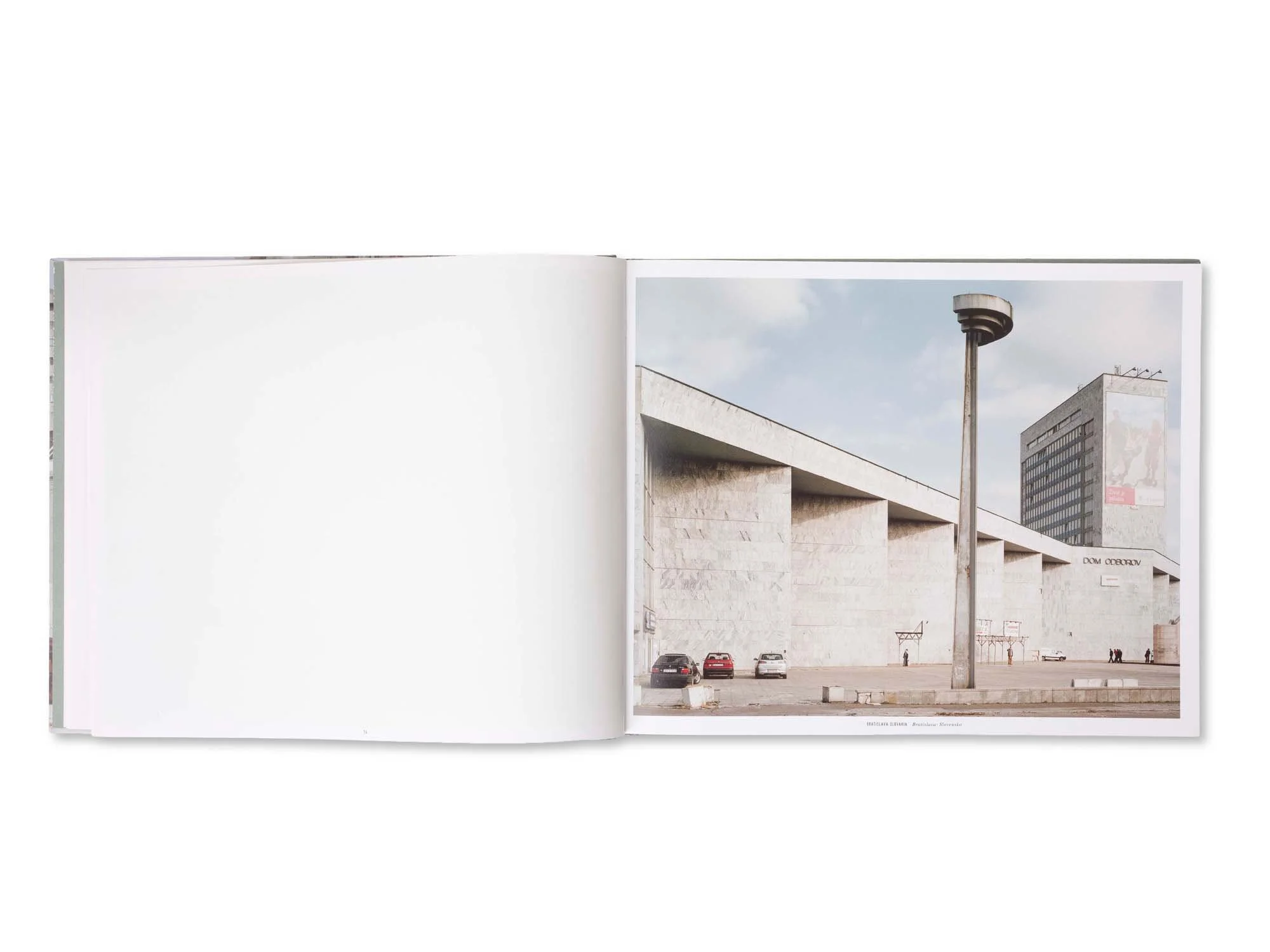 Fotografie eines modernen Gebäudes mit parkenden Autos und einer Straßenlaterne im Vordergrund, im Stadtzentrum.