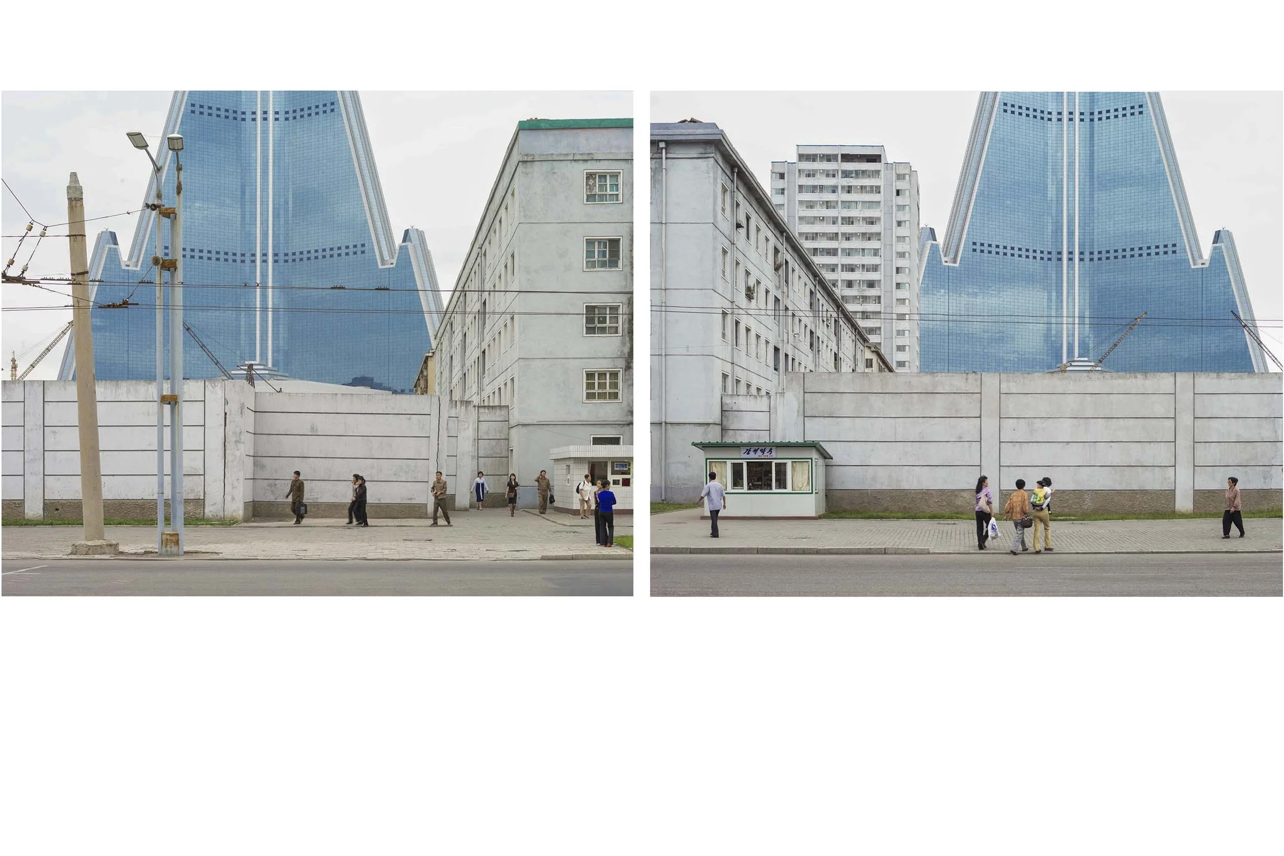 Ryugyŏng-Hotel in Pjöngjang, Nordkorea: Die pyramidenförmige Silhouette des unverwechselbaren 105-Etagen-Bauwerks ragt hinter Wohnblöcken und einer Mauer empor. Nach jahrelangem Baustopp erhielt der imposante Wolkenkratzer erst spät seine charakteris