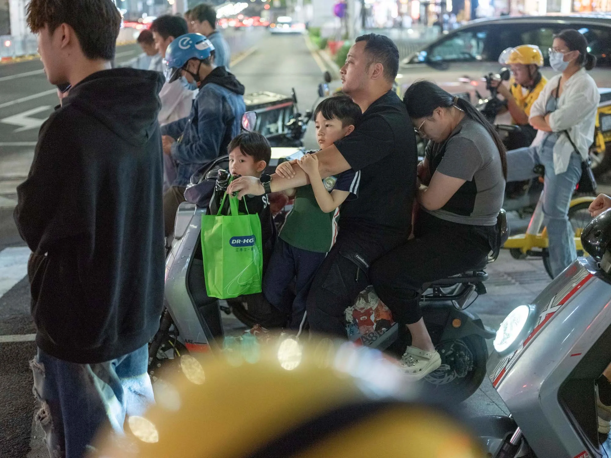 Documentary photograph by Roman Bezjak highlighting Shenzhen as a global leader in e-mobility, showing residents, families, and delivery workers navigating the city on electric scooters, family